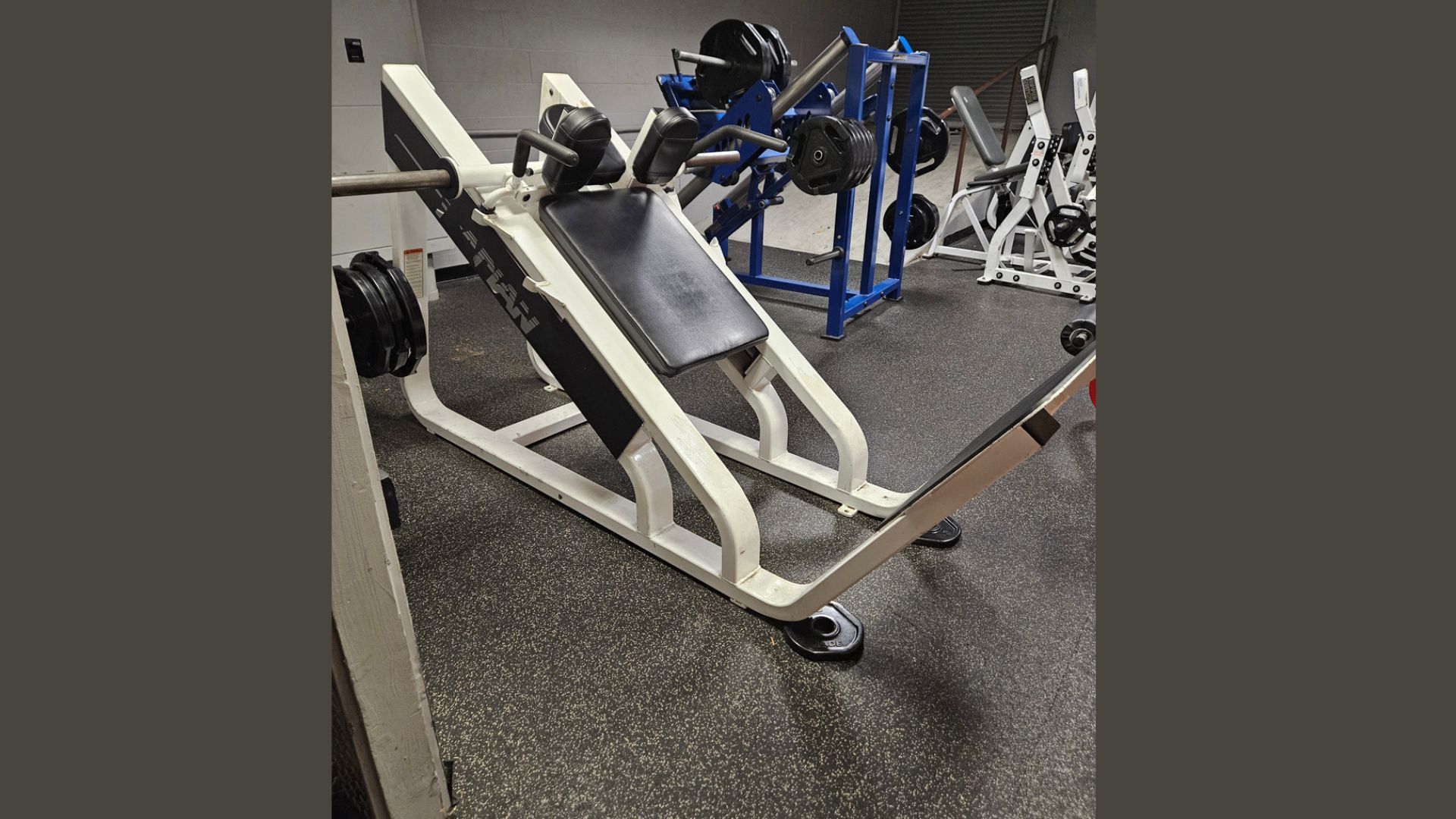 A gym room featuring various exercise equipment, including weights and machines, arranged for workout sessions.