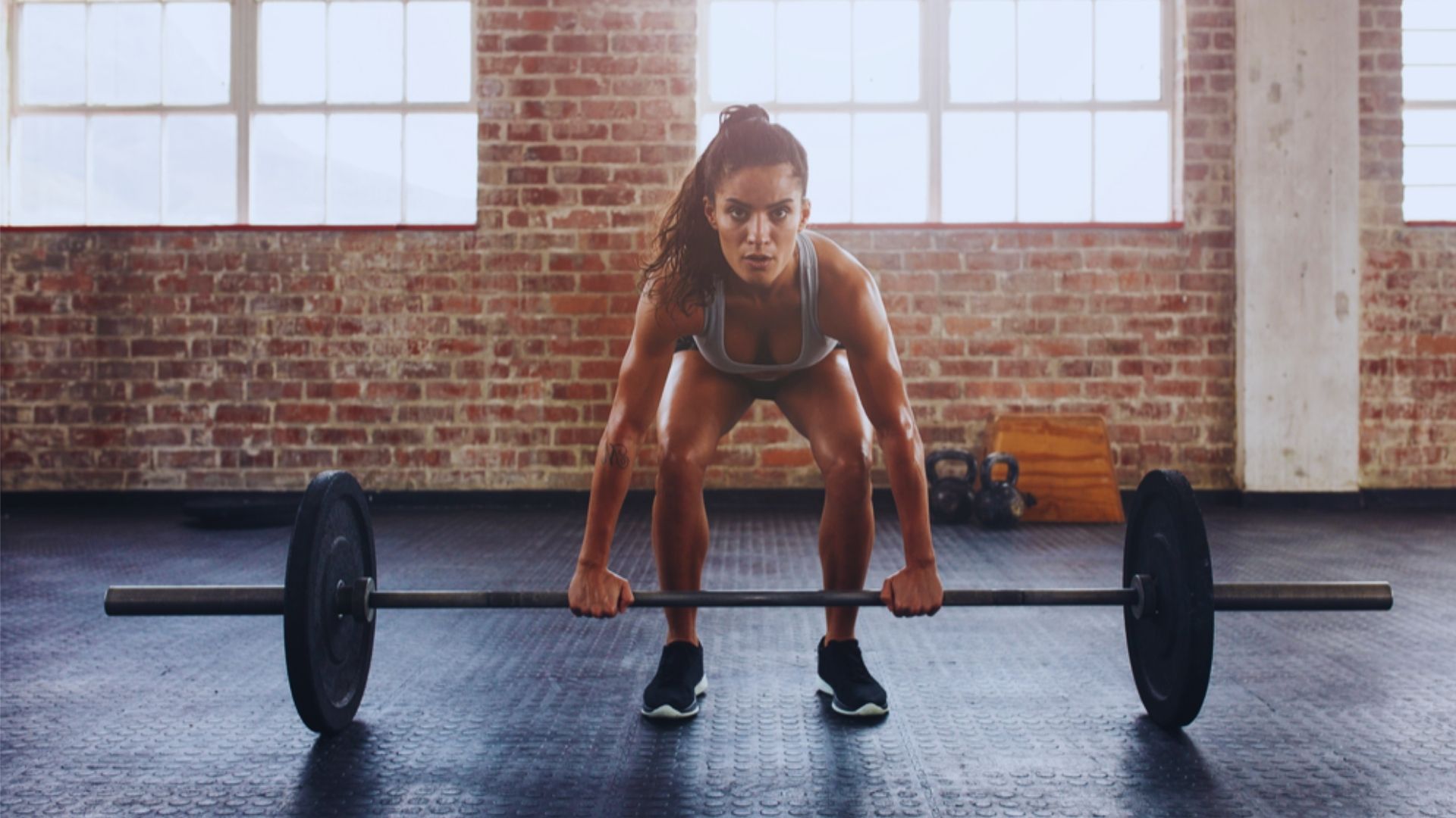 A woman performs a squat with a barbell, showcasing her fitness routine in a well-equipped gym environment.
