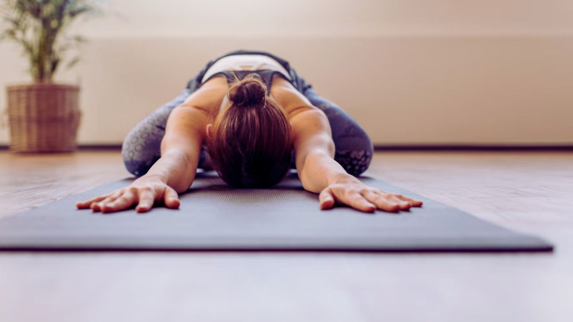 A woman practicing yoga on a mat, demonstrating a focused pose in a serene environment.