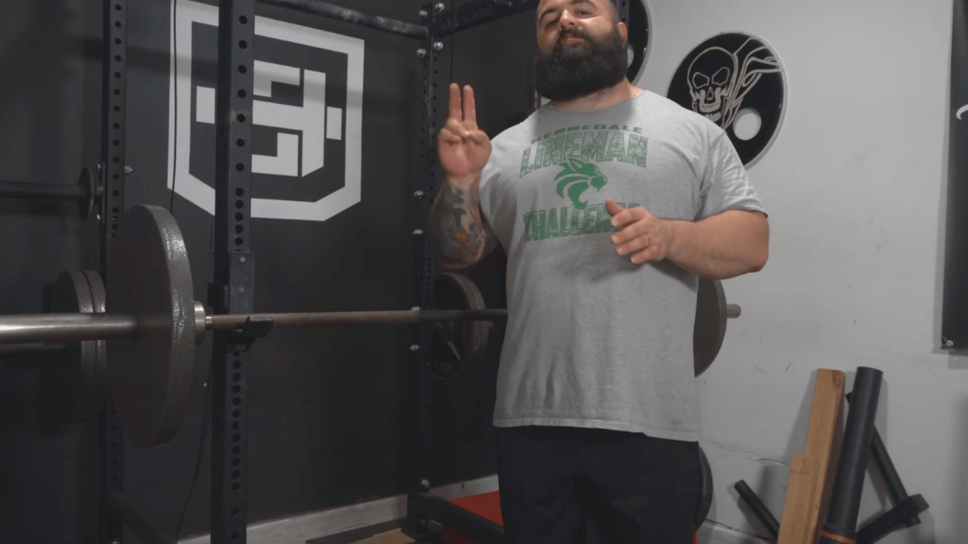 A bearded man stands confidently in front of a barbell, illustrating strength training concepts for back off sets.