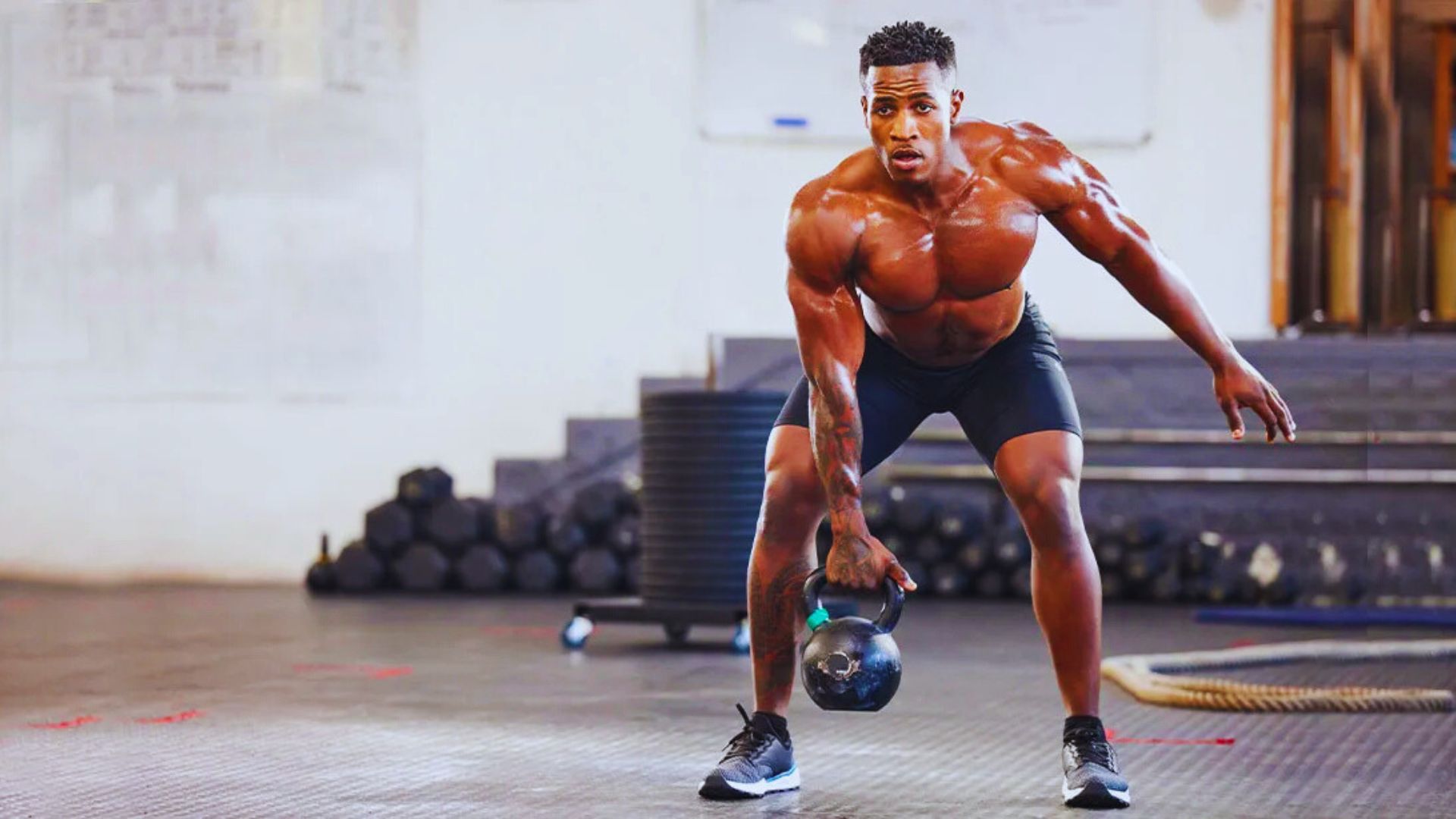 In a gym, a man is performing a kettlebell lift, showcasing his workout effort.