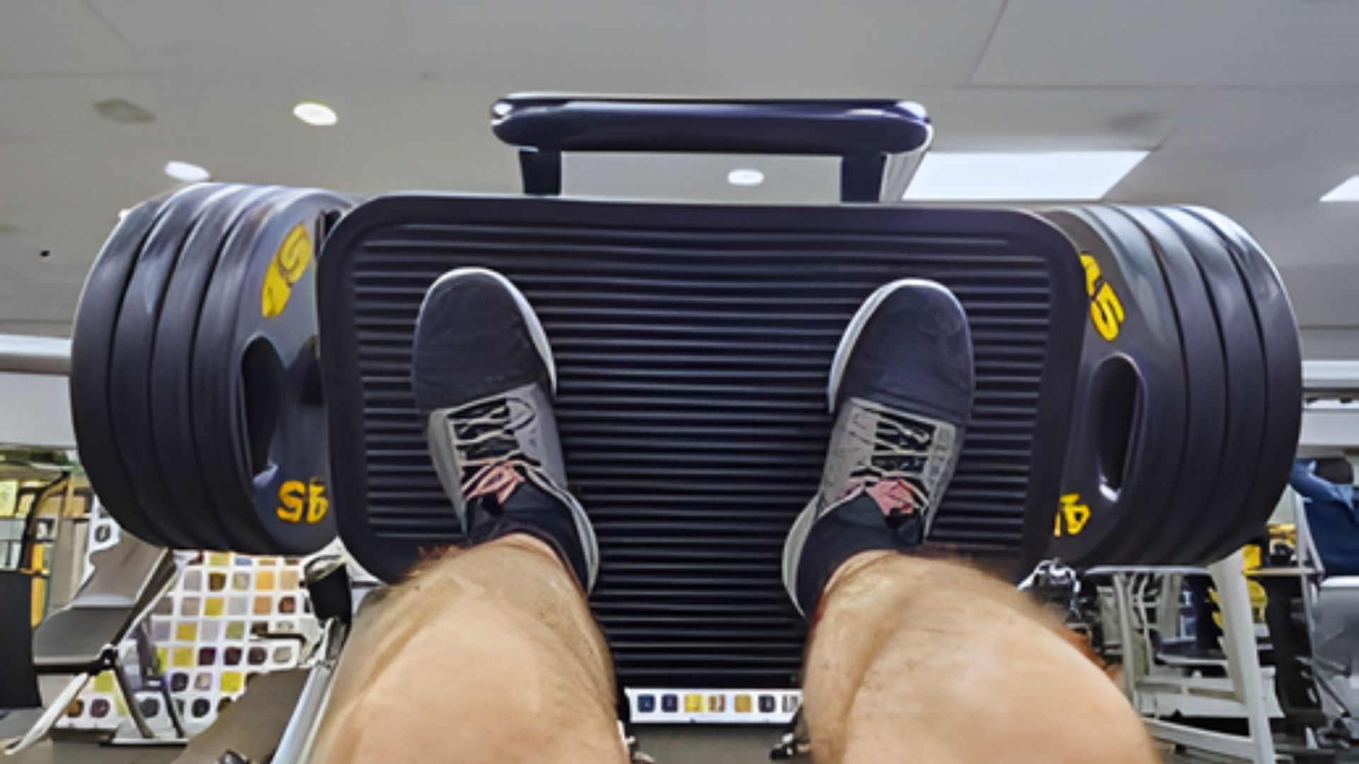 A person sitting on a gym bench, focused on a workout routine with weights nearby.