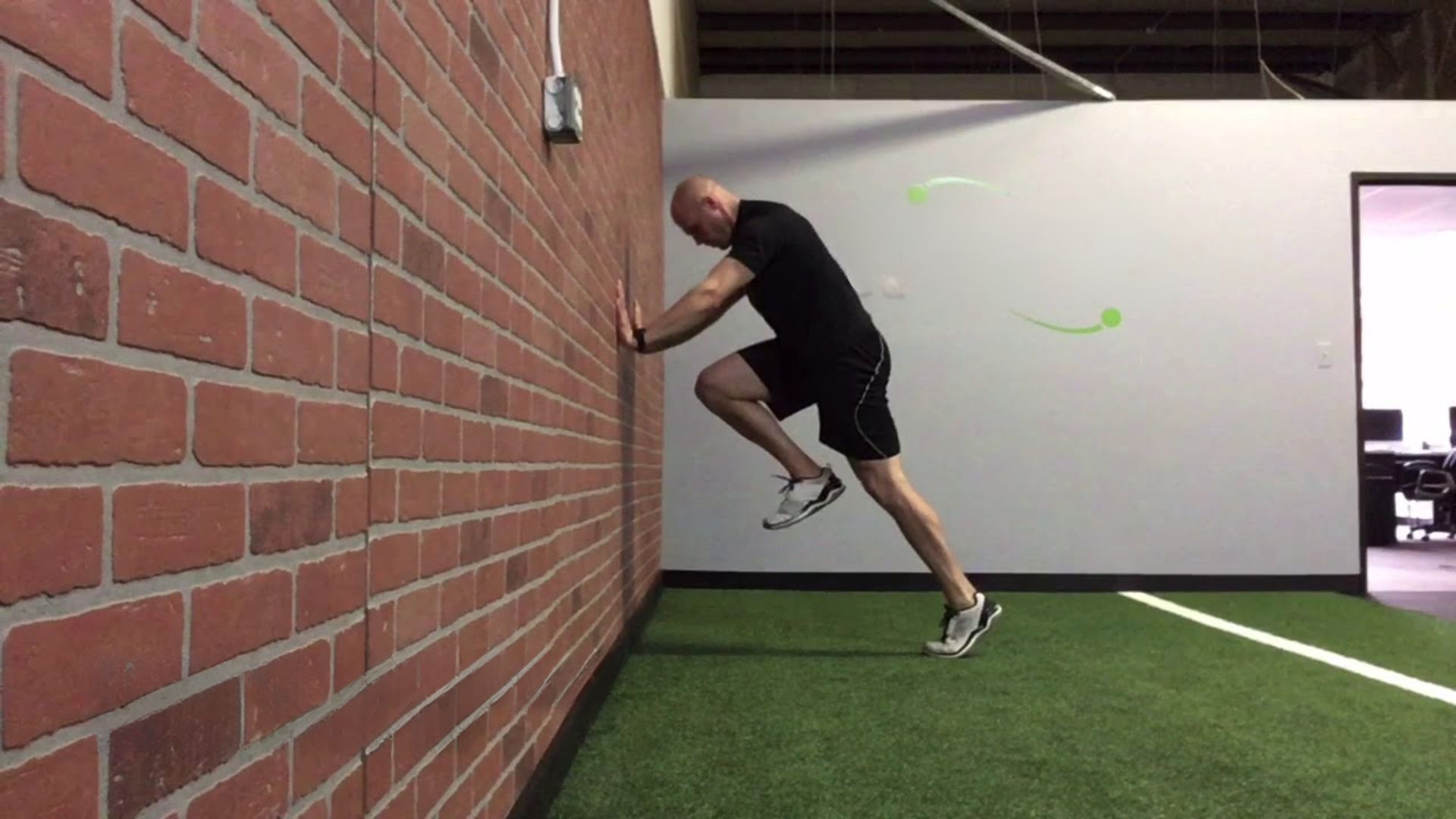 An indoor gym scene features a man leaping off a wall, demonstrating his skills in parkour or gymnastics.
