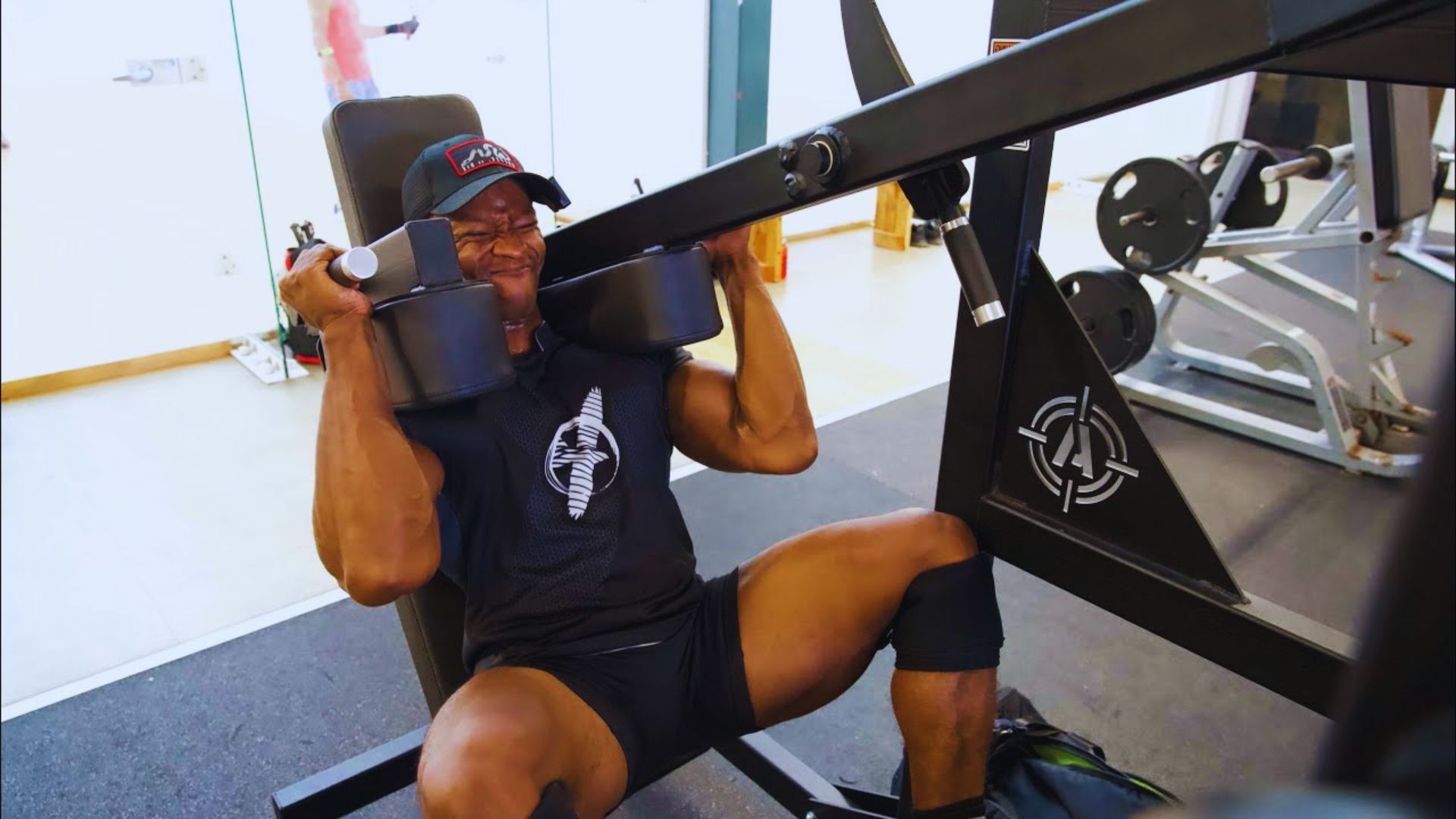 A man performs a bench press exercise in a gym, focusing on lifting a barbell above his chest.
