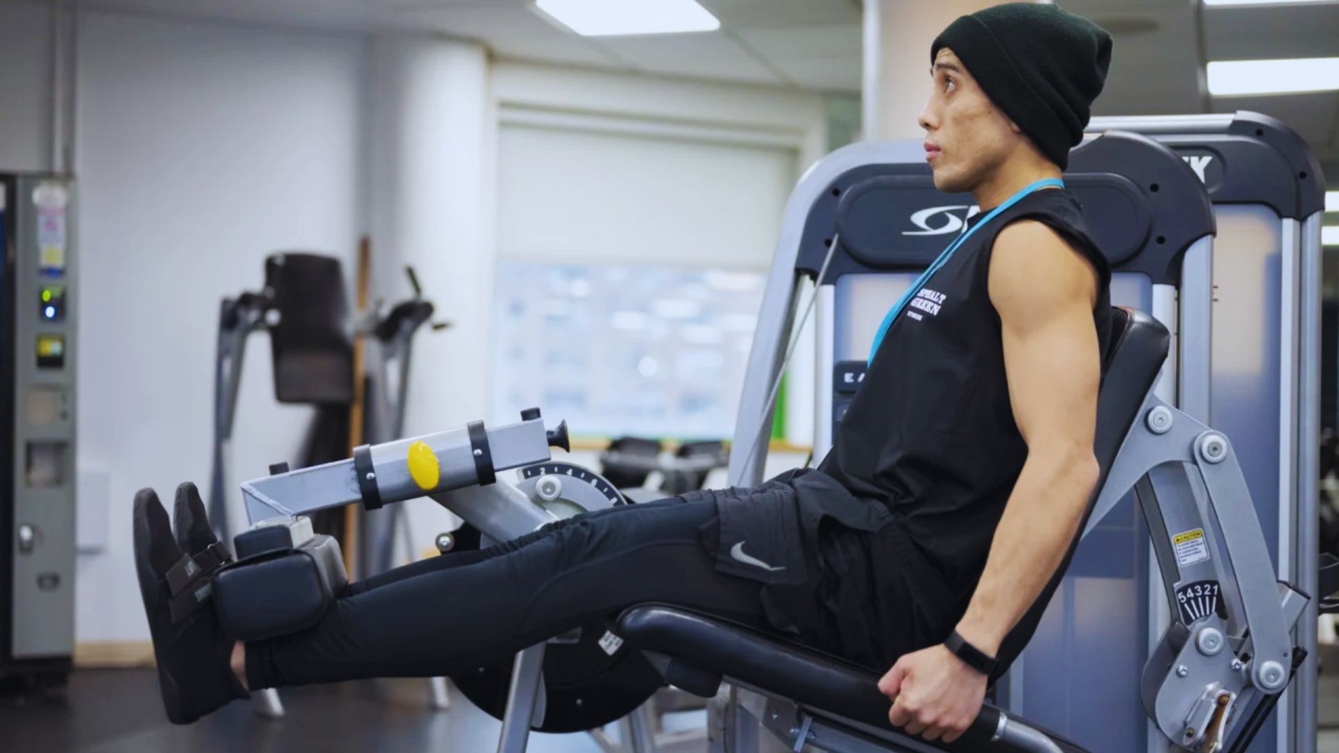A man using a gym machine, focused on his workout in a well-equipped fitness center.