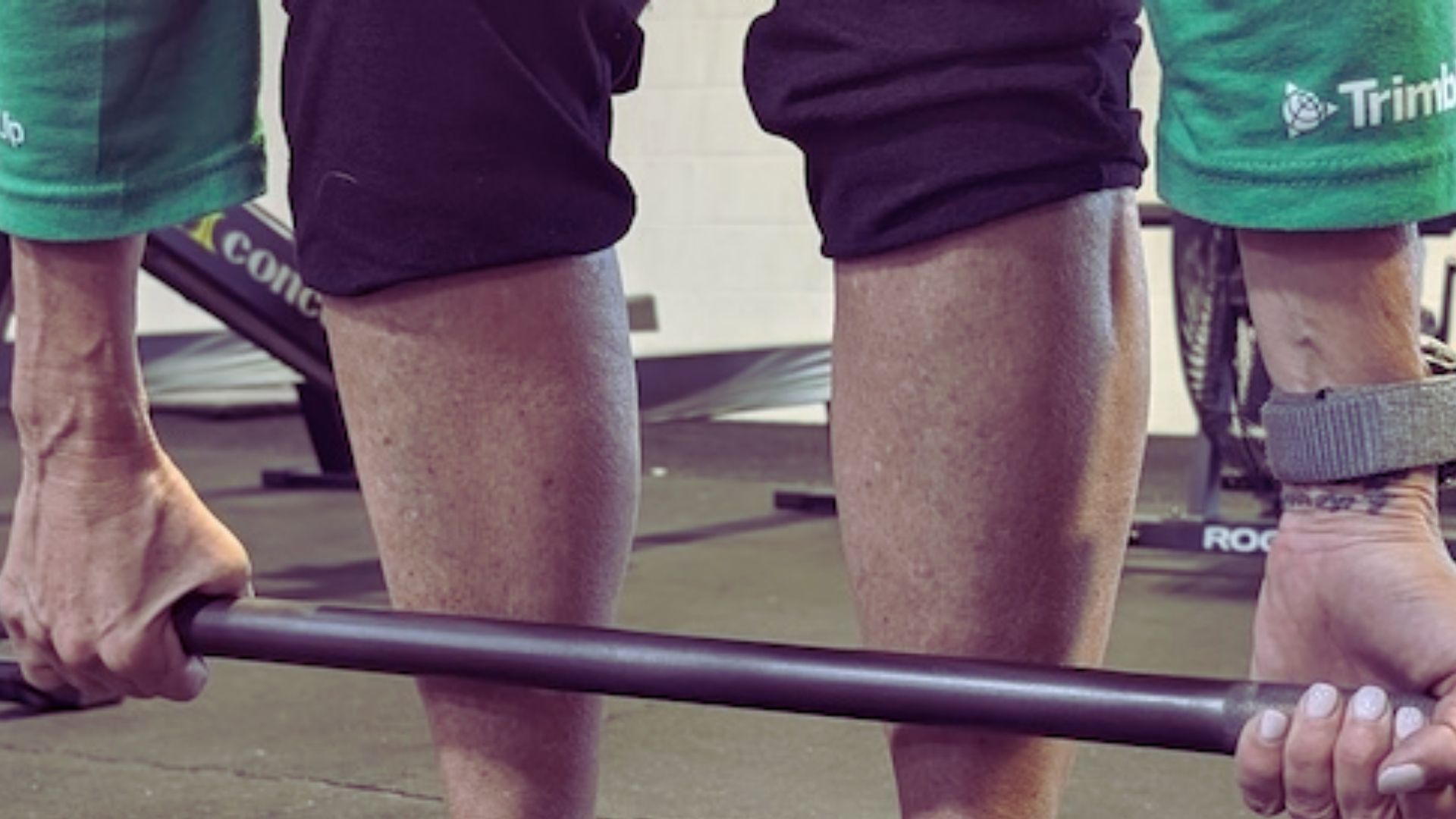 An individual holds a barbell in a gym setting, focused on their weightlifting routine.