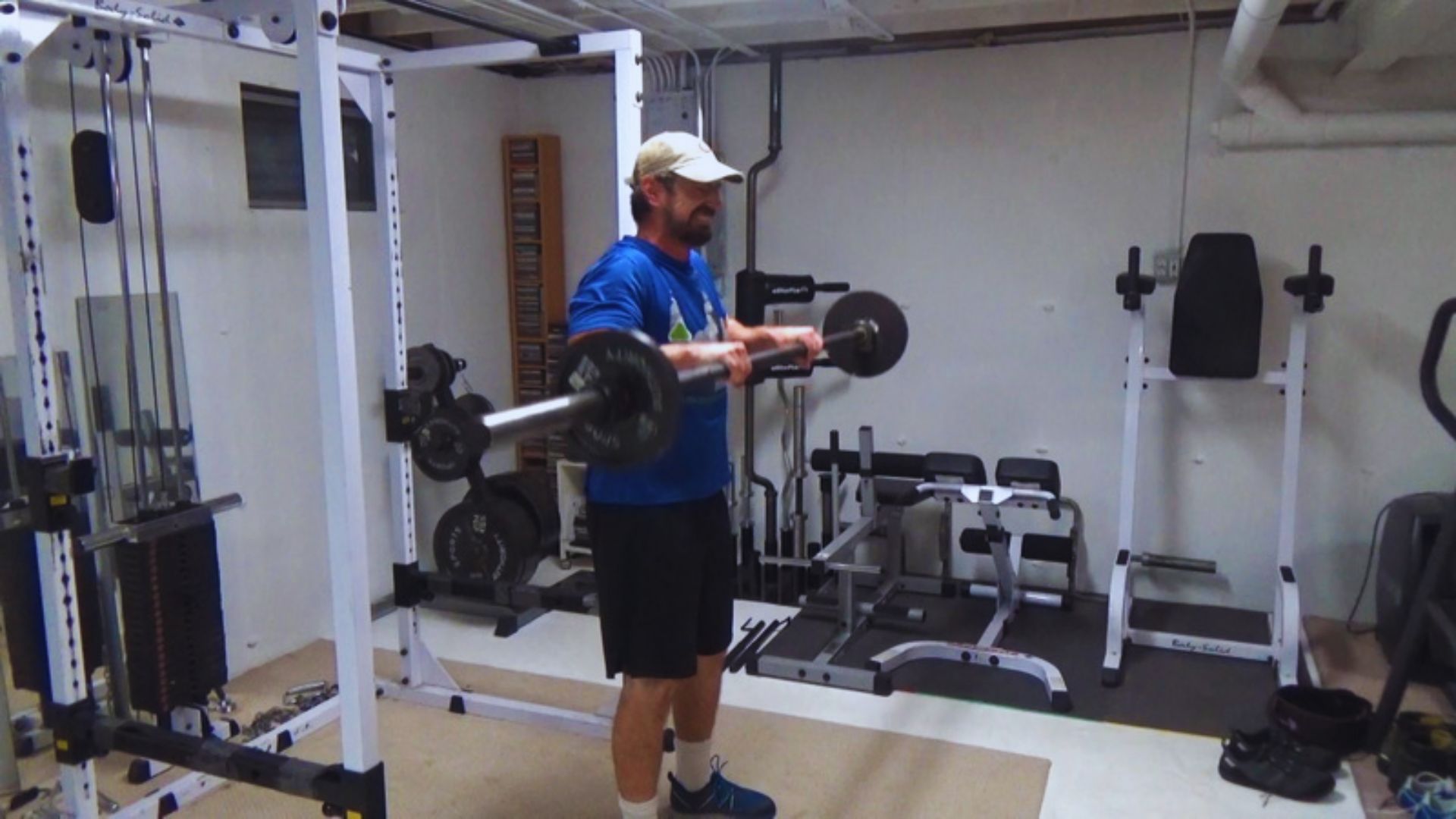 A man performs reverse curls with a barbell in a gym, focusing on building stronger biceps and forearms.