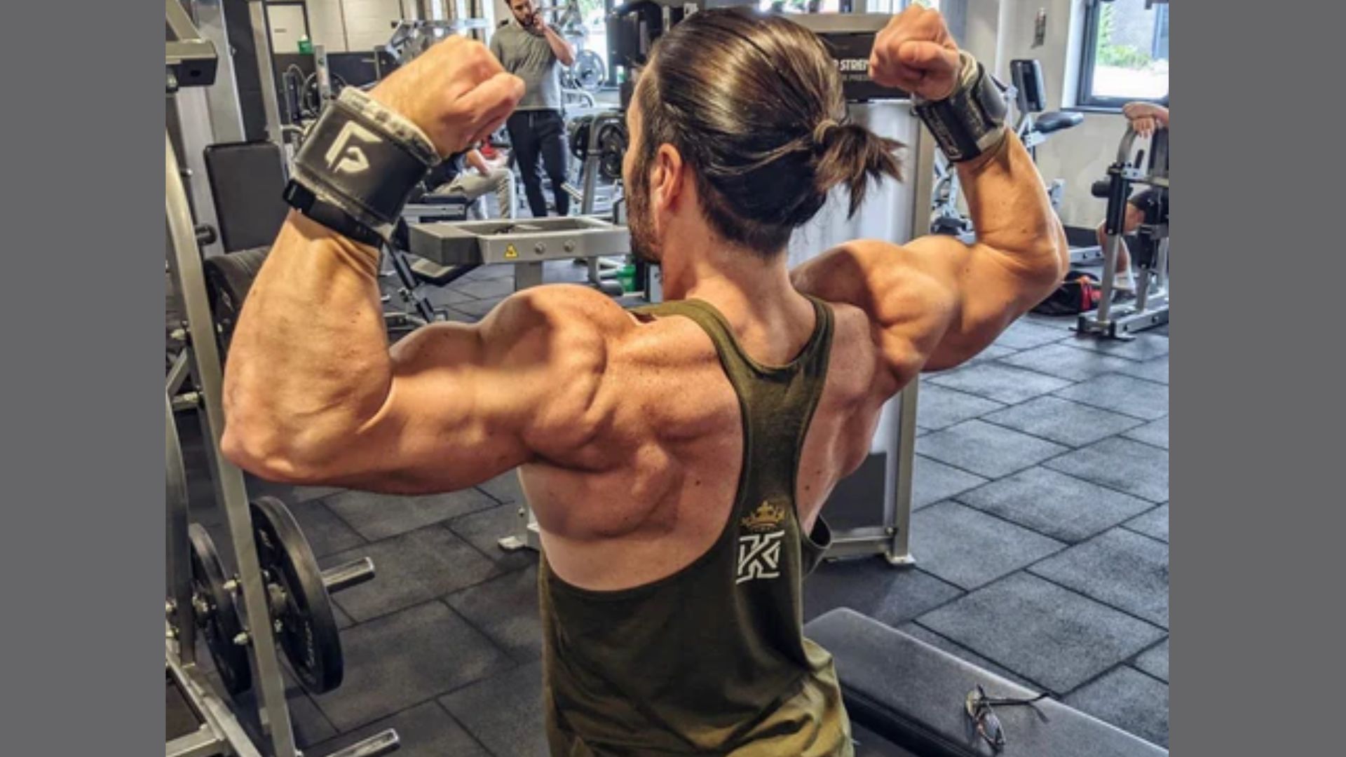A man flexes his muscles in a gym, showcasing strength and fitness, related to factors affecting gym pump duration.