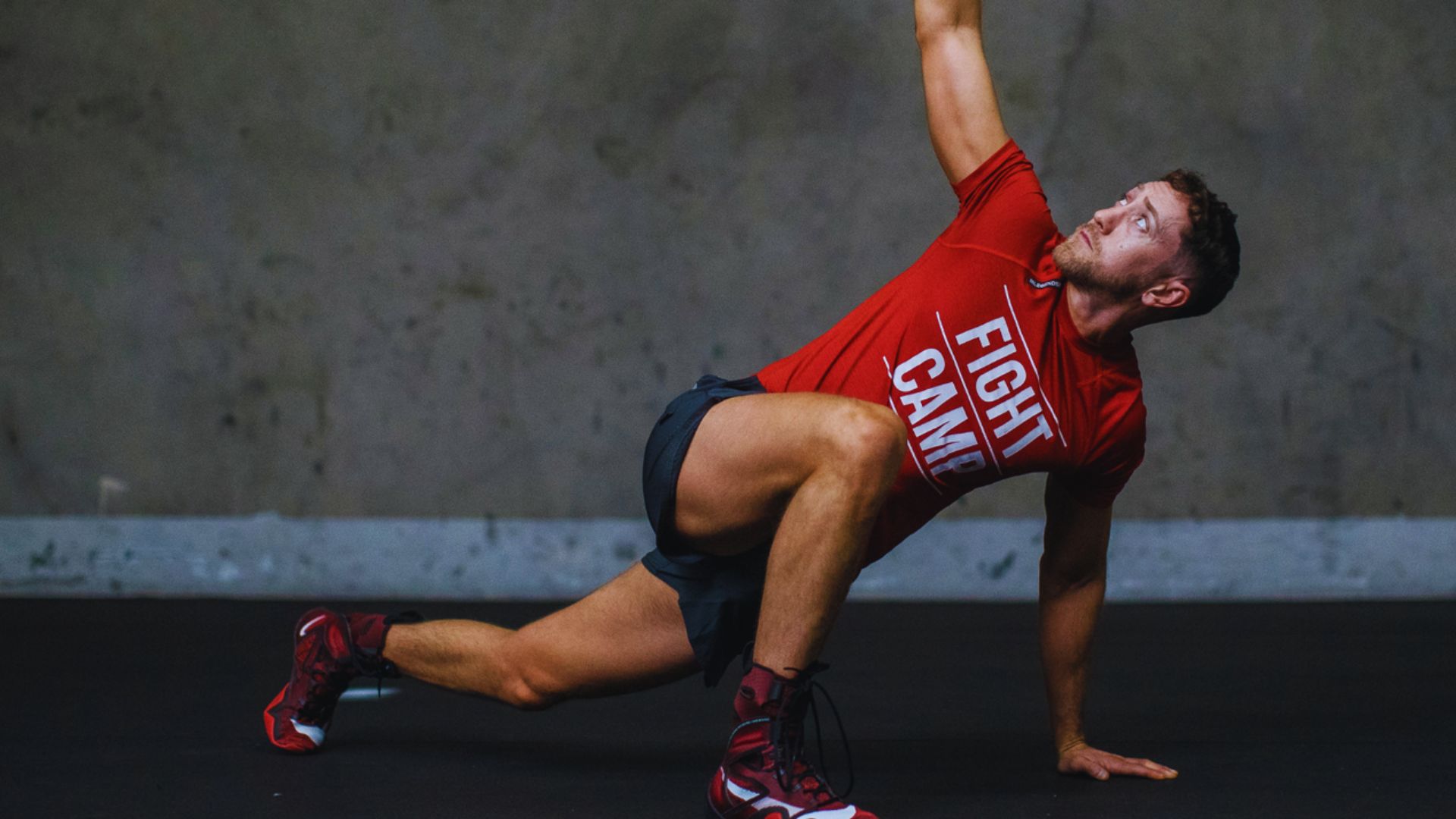 A man in a red shirt performs a push-up as part of his post-workout stretch routine.