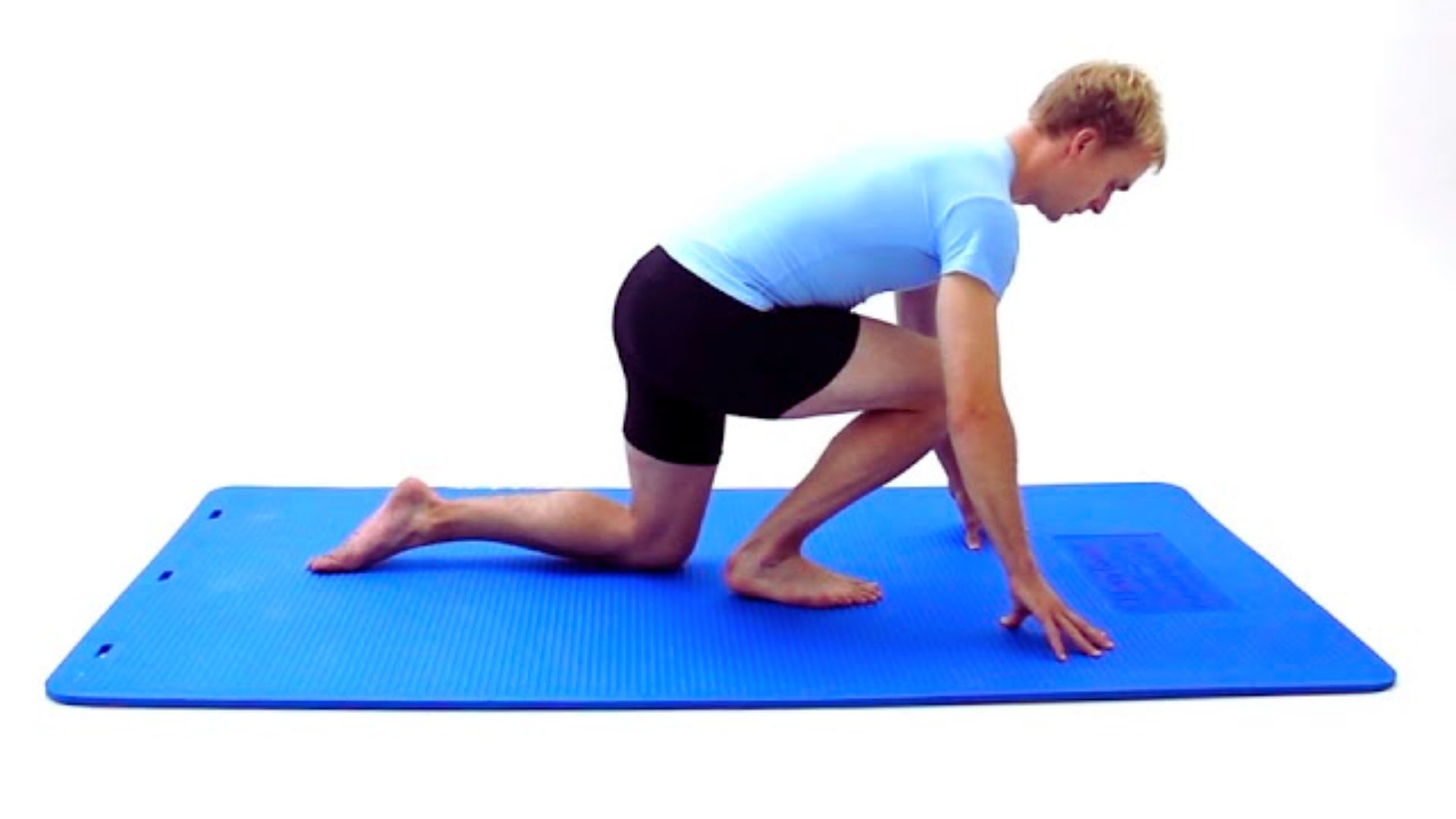 A man performs a yoga pose on a blue mat, demonstrating balance and focus in a serene environment.