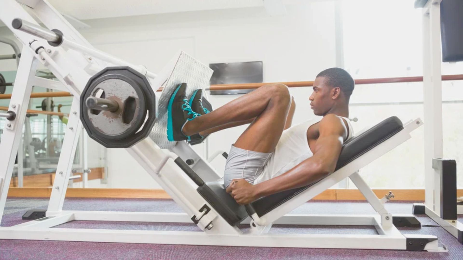 A man exercises on a leg press machine, focusing on his workout in a gym setting.