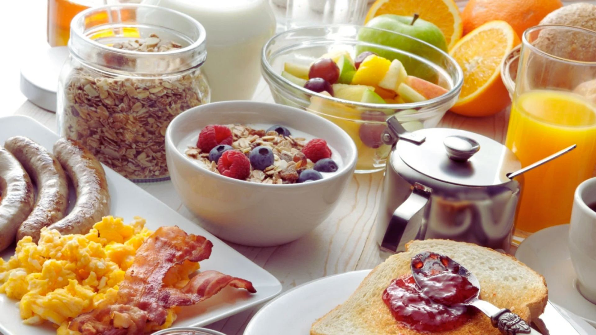 A breakfast table set with an assortment of food items, including fruits, pastries, and beverages.