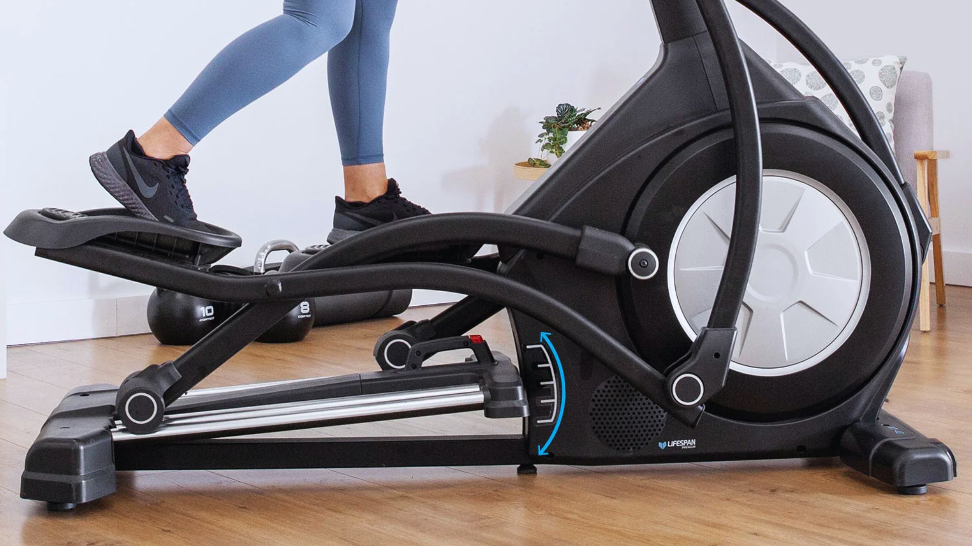 A woman stands on an elliptical bike, preparing for a workout in a fitness setting.