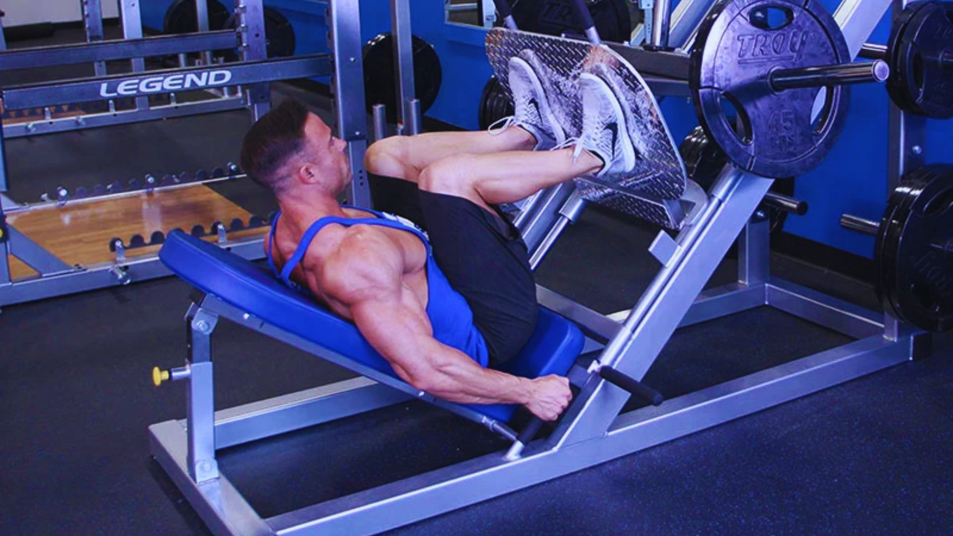 A man performs a leg press on a machine, focusing on lowering the weight for a full stretch of his legs.