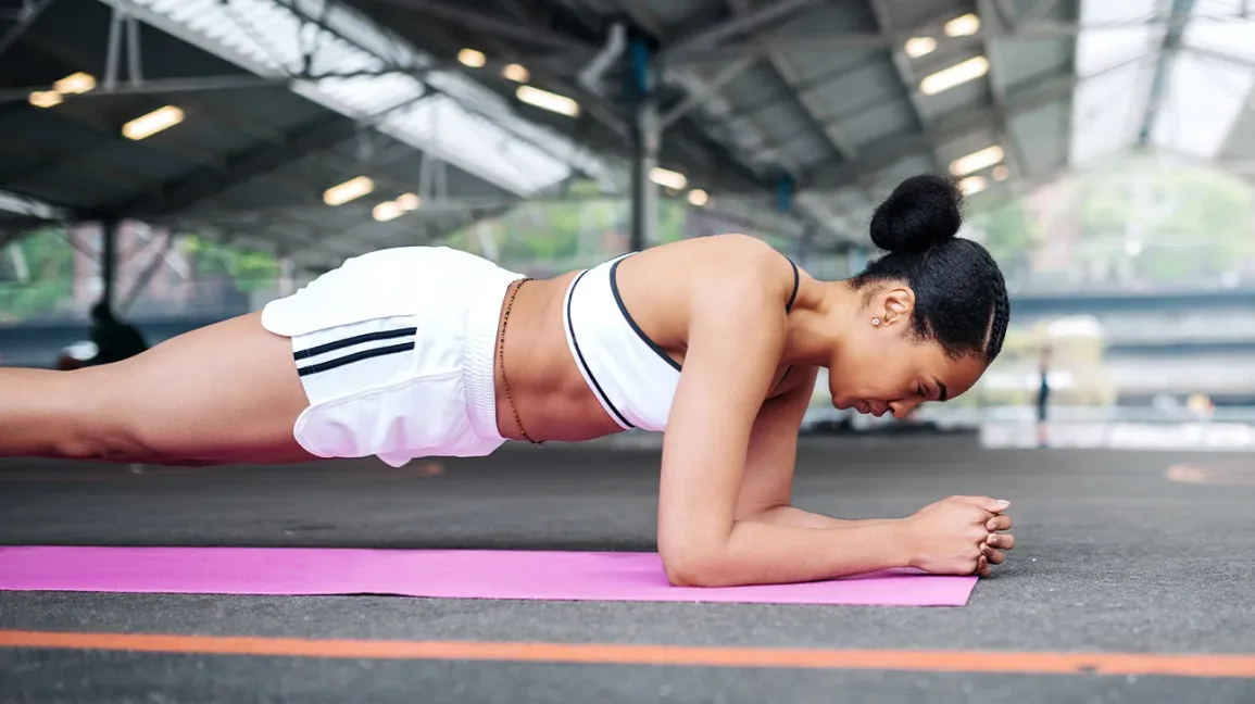 A woman performing an exercise targeting her core and glutes, demonstrating proper form and focus.