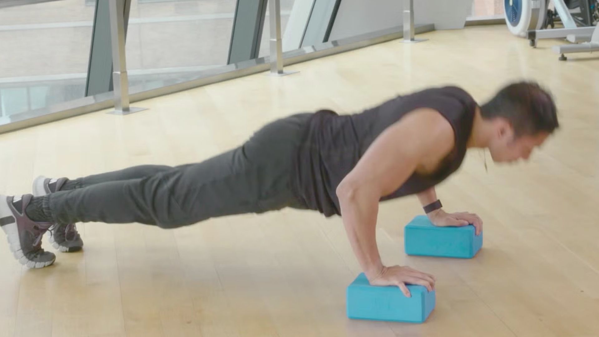 A man performing push-ups on a blue exercise block, focusing on strength training and fitness.