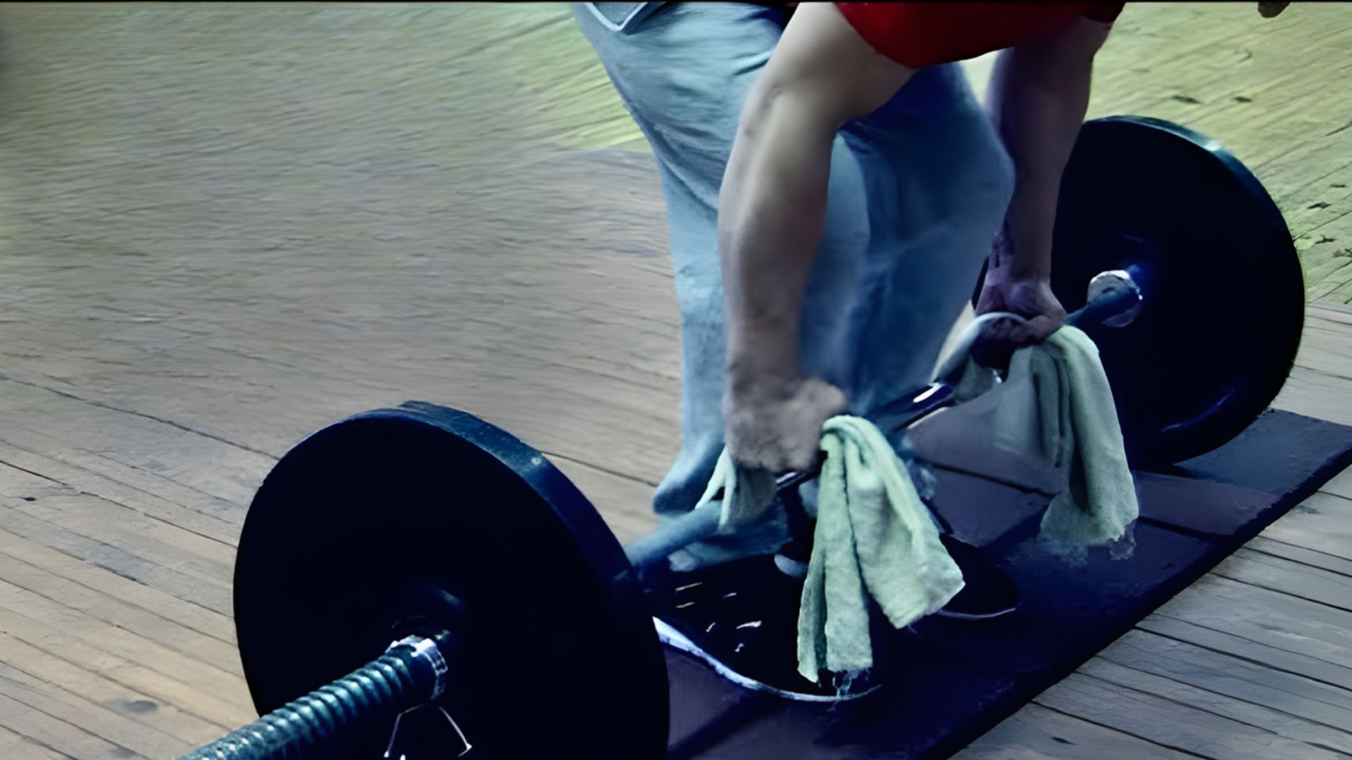 3. A man performs a barbell lift on a gym floor, demonstrating strength and determination in his workout routine.