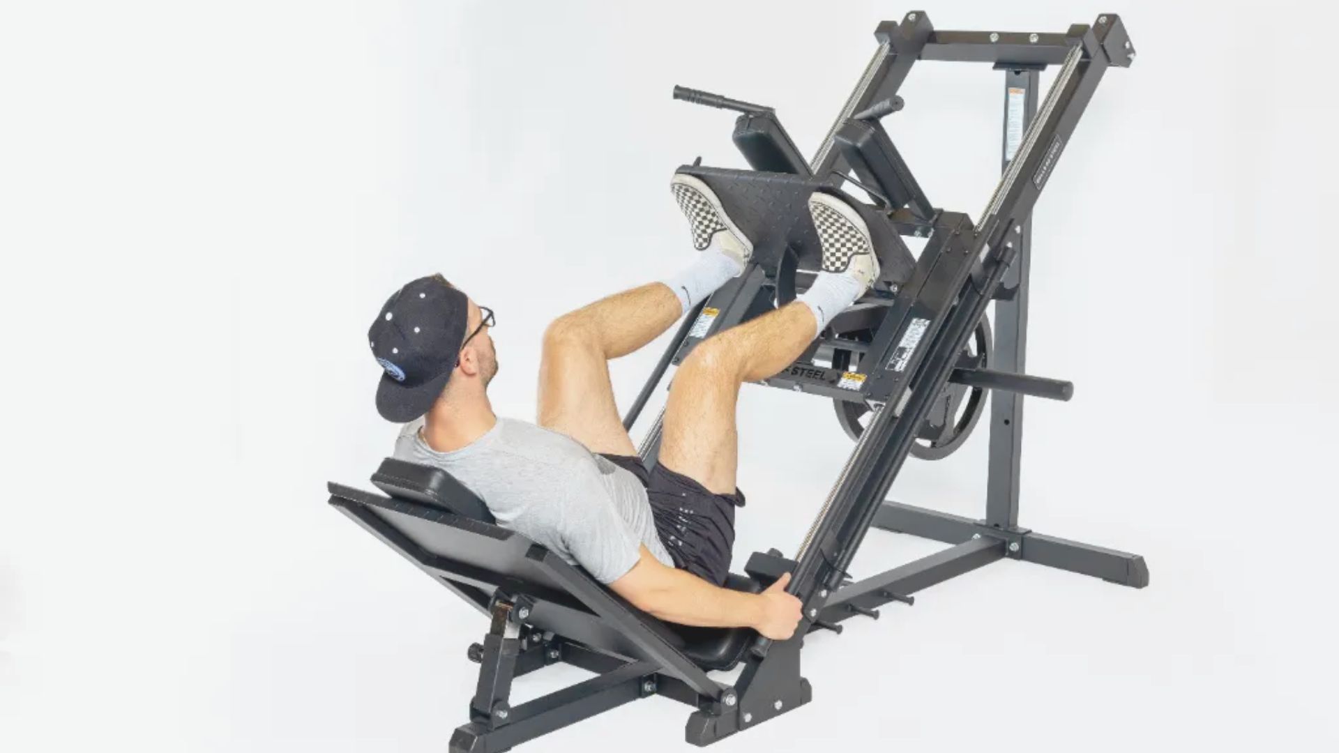 A man exercises on a leg press machine, focusing on his workout in a gym setting.