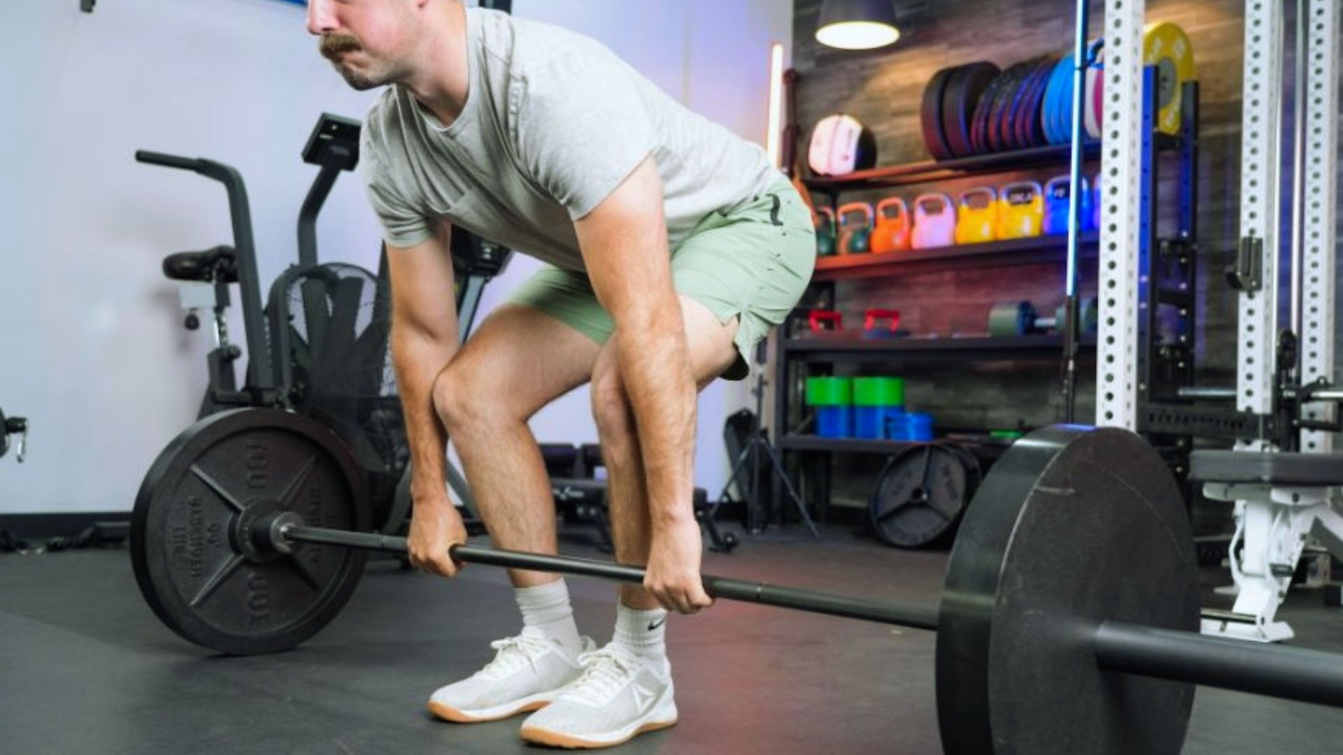 A man performs a barbell squat in a gym, focusing on his form and balance while lifting weights.
