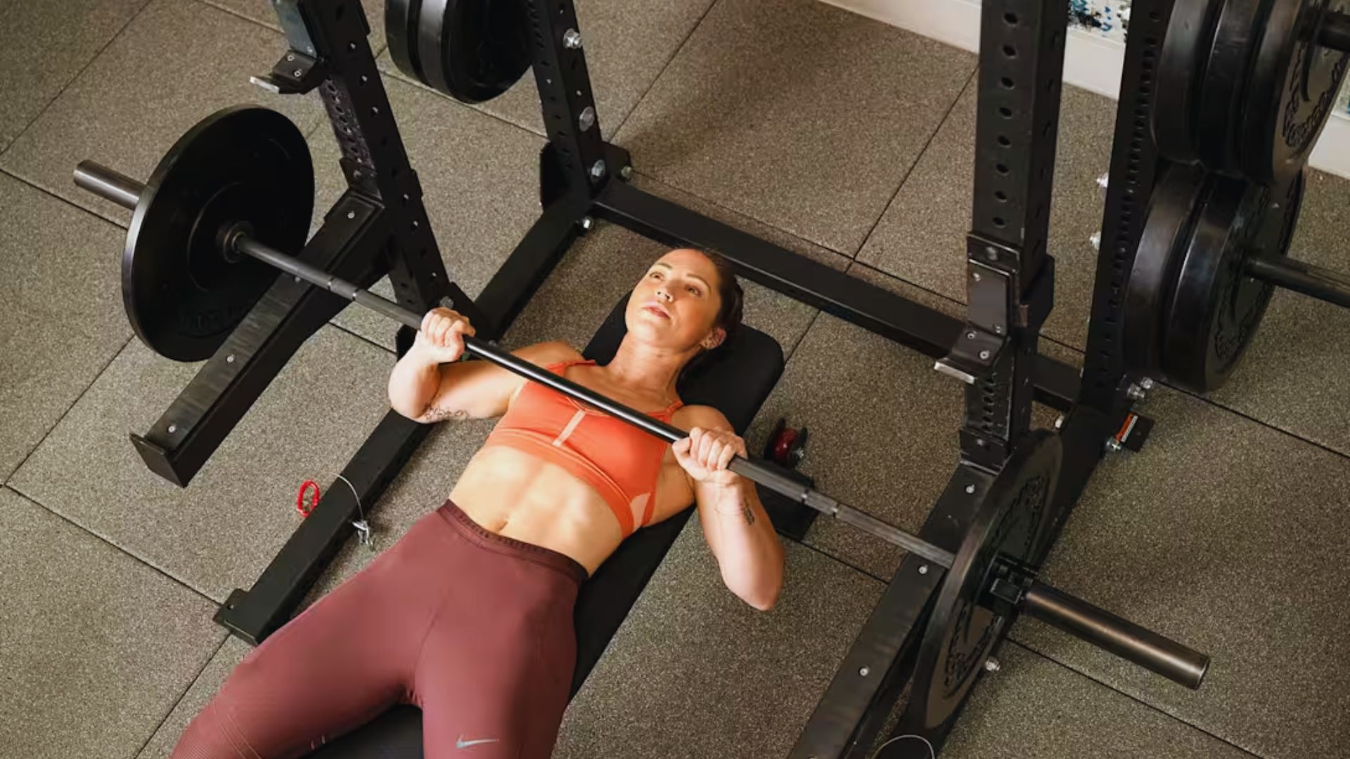 A woman is lifting weights on a bench press in a gym, demonstrating her commitment to physical fitness.