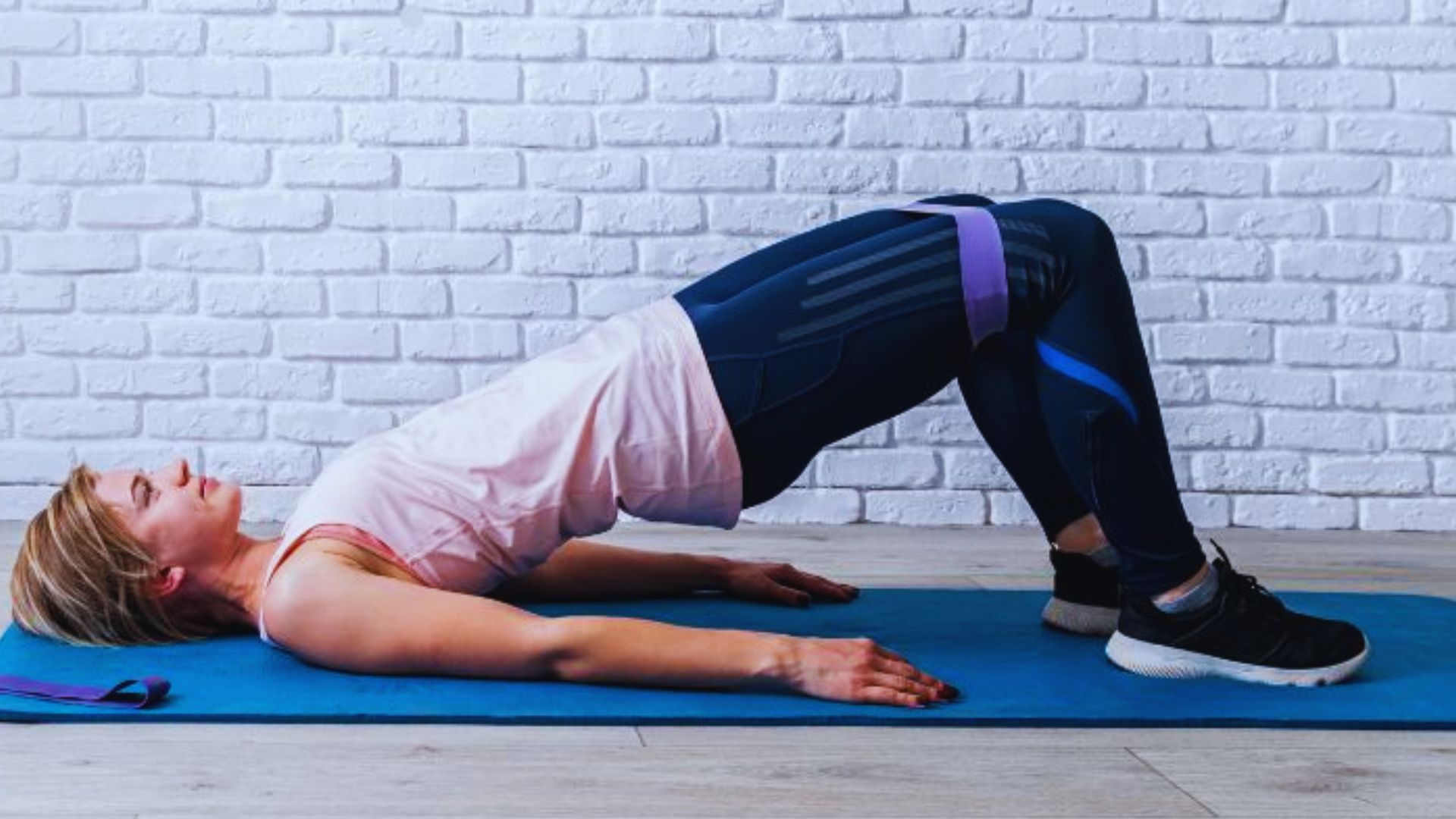 A woman is engaged in a side plank exercise on a blue mat, demonstrating strength and stability.