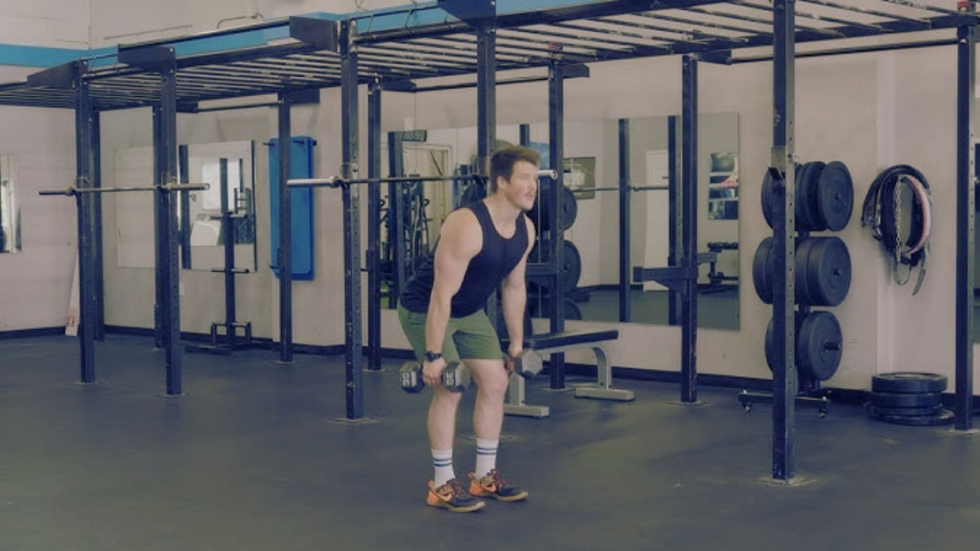 A man is engaged in a squat at the gym, emphasizing correct posture and movement for effective weight training.