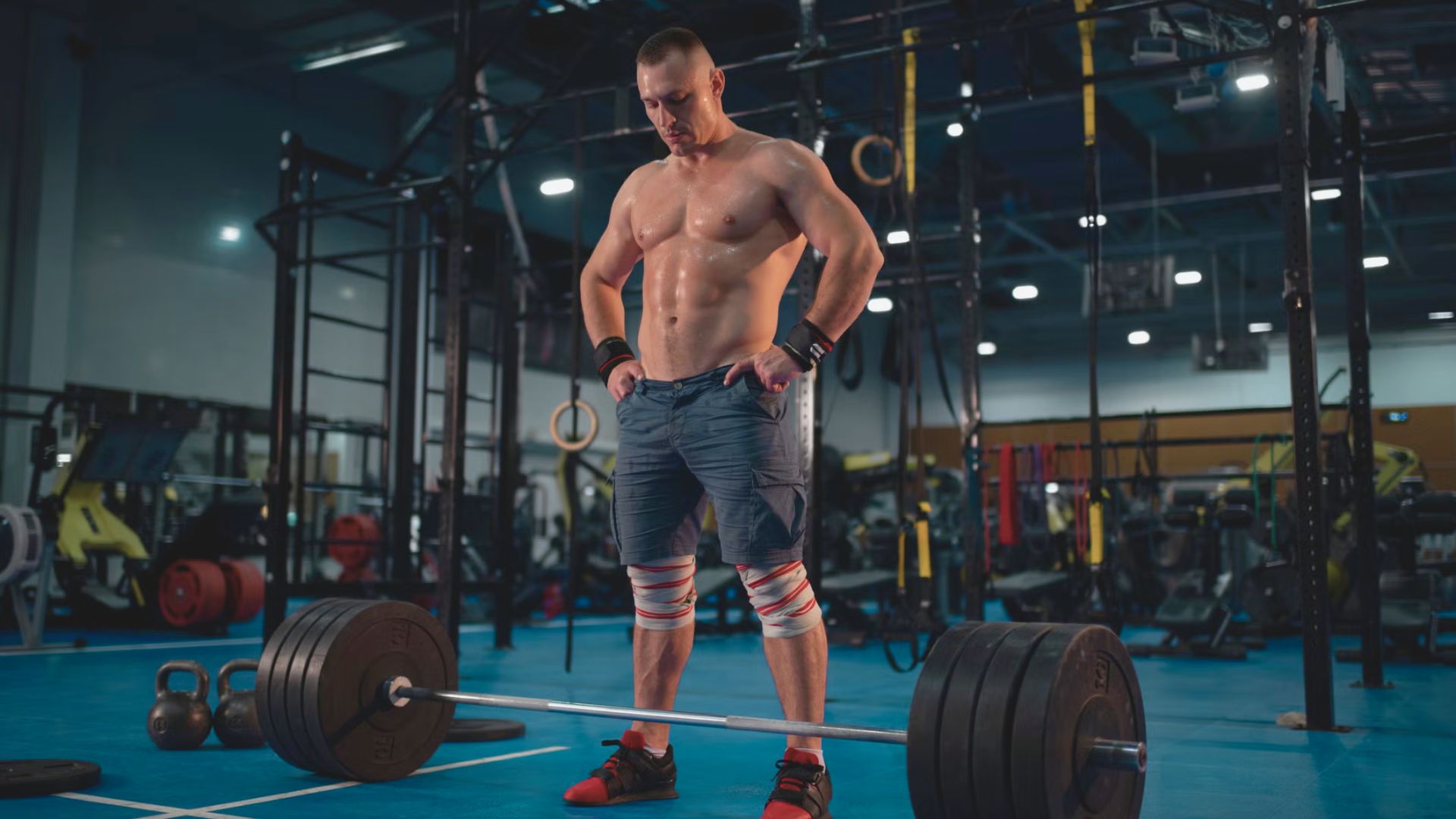 A man stands in a gym, holding a barbell, demonstrating strength training techniques for back off sets.