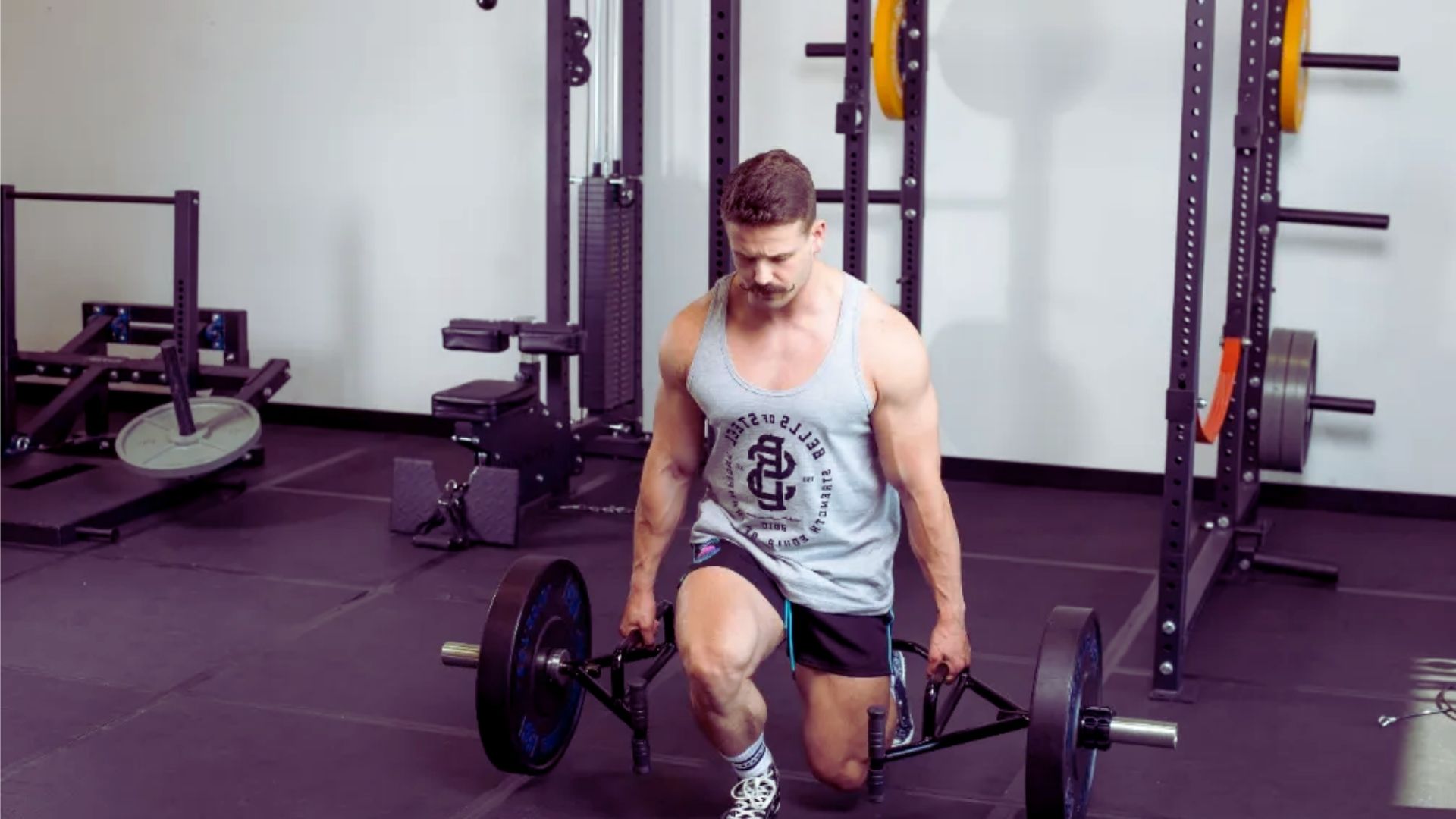 A man squats with a barbell in a gym, focusing on strength training and proper form.