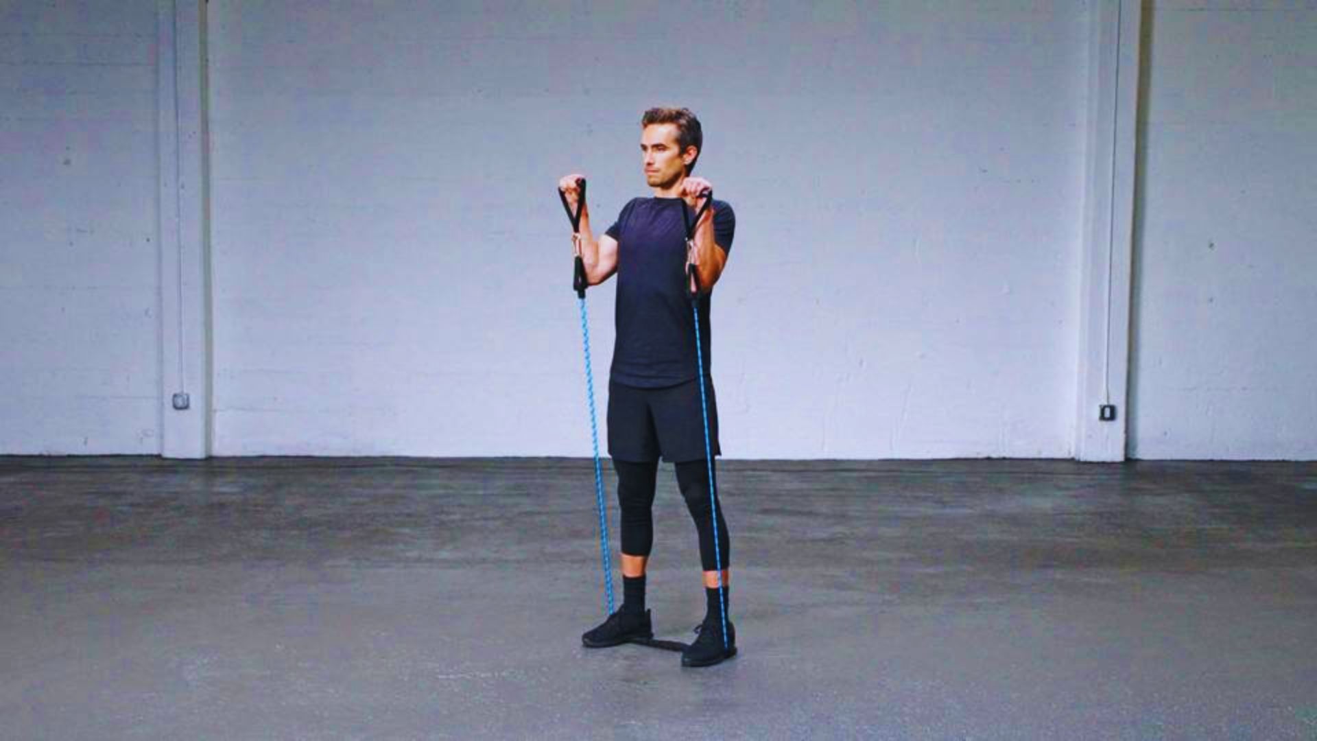 man holds a resistance band in an empty room, preparing for a workout or exercise session.
