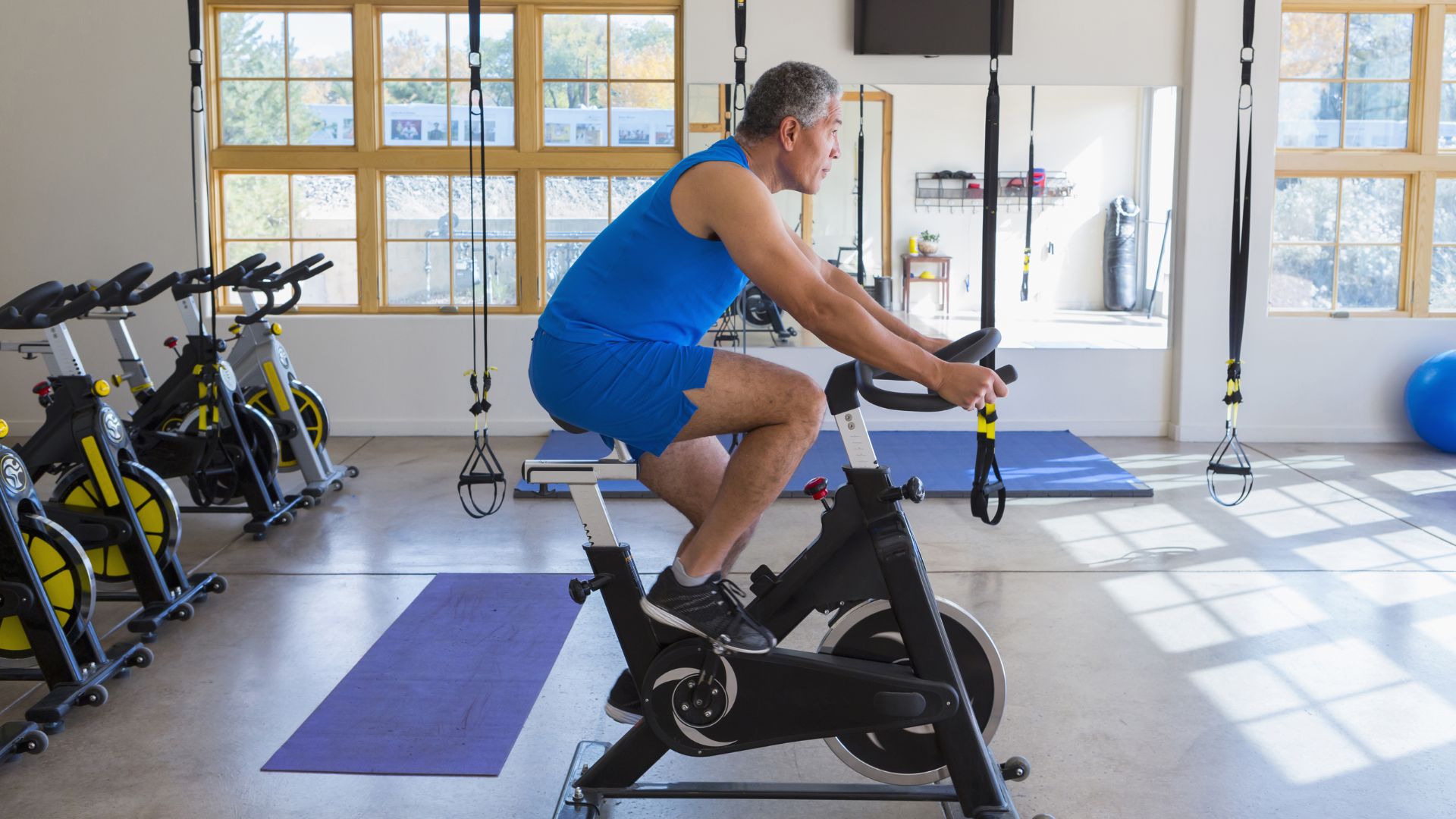 1. A man is exercising on a stationary bike in a well-equipped gym.