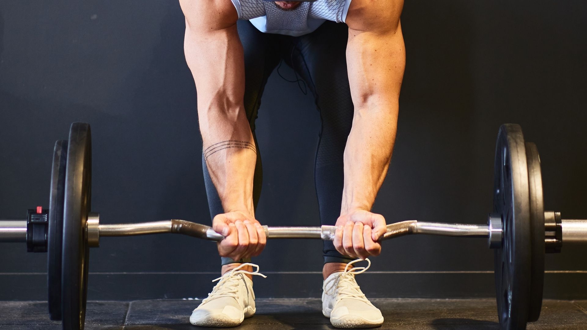 A man is lifting a barbell above his head in a gym setting, demonstrating strength and focus.