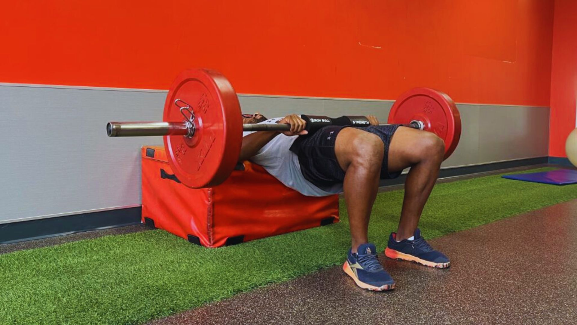 A man performs a squat while holding a barbell across his shoulders in a gym setting.