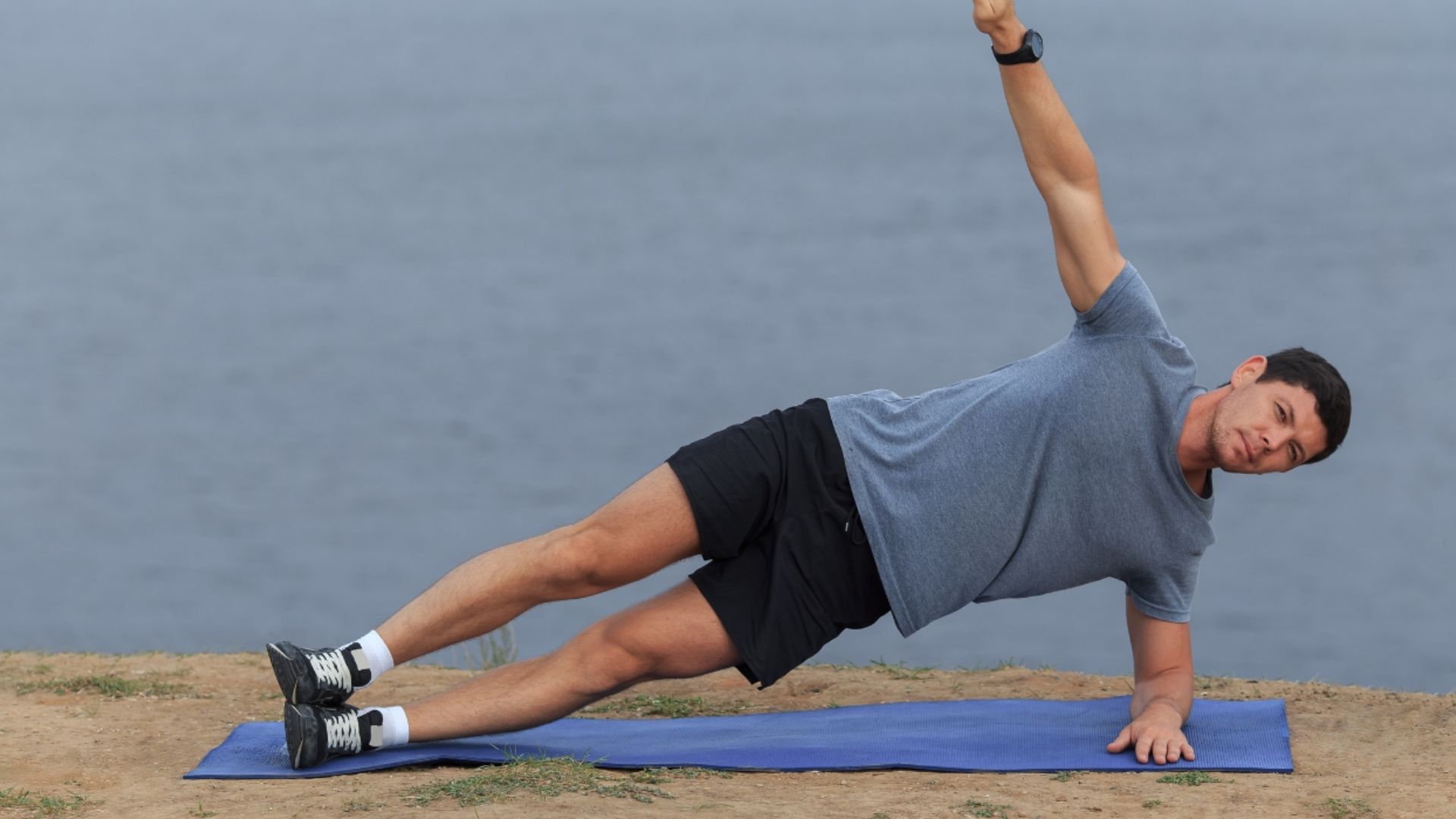A man performs an exercise on a blue mat, focusing on his form and technique.