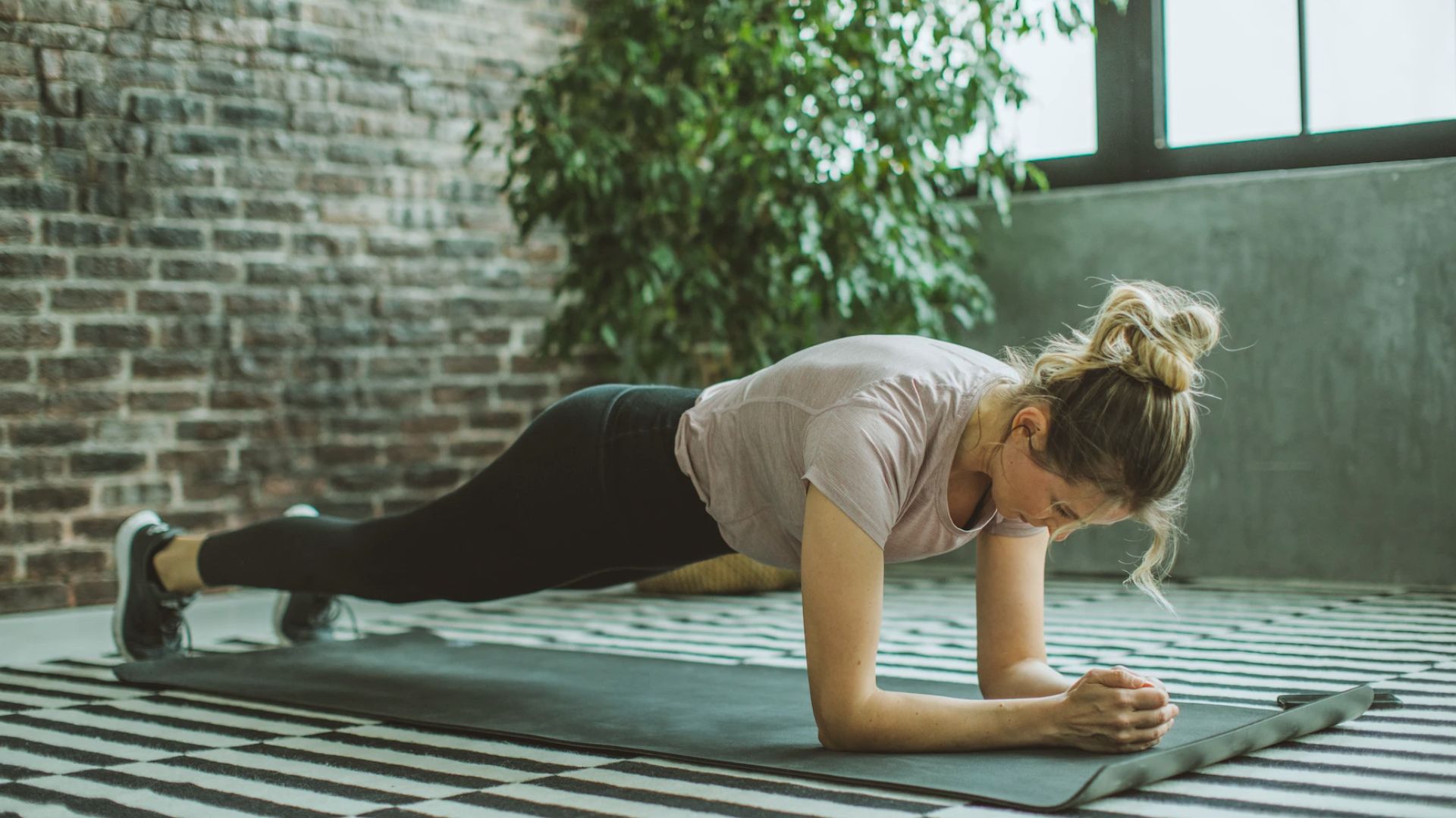 A woman performing push-ups on a fitness mat, focusing on her form and strength during the exercise.