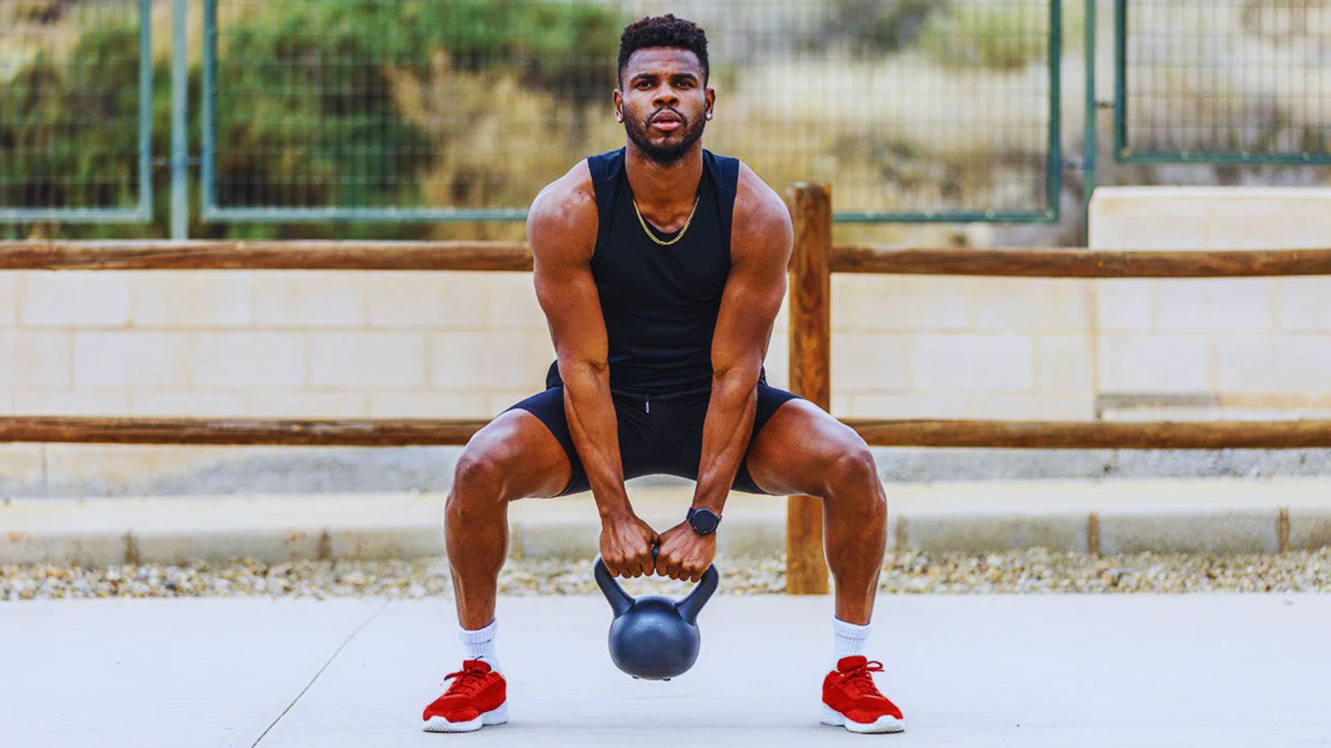 A man squats while holding a kettlebell, demonstrating strength training and proper exercise form.