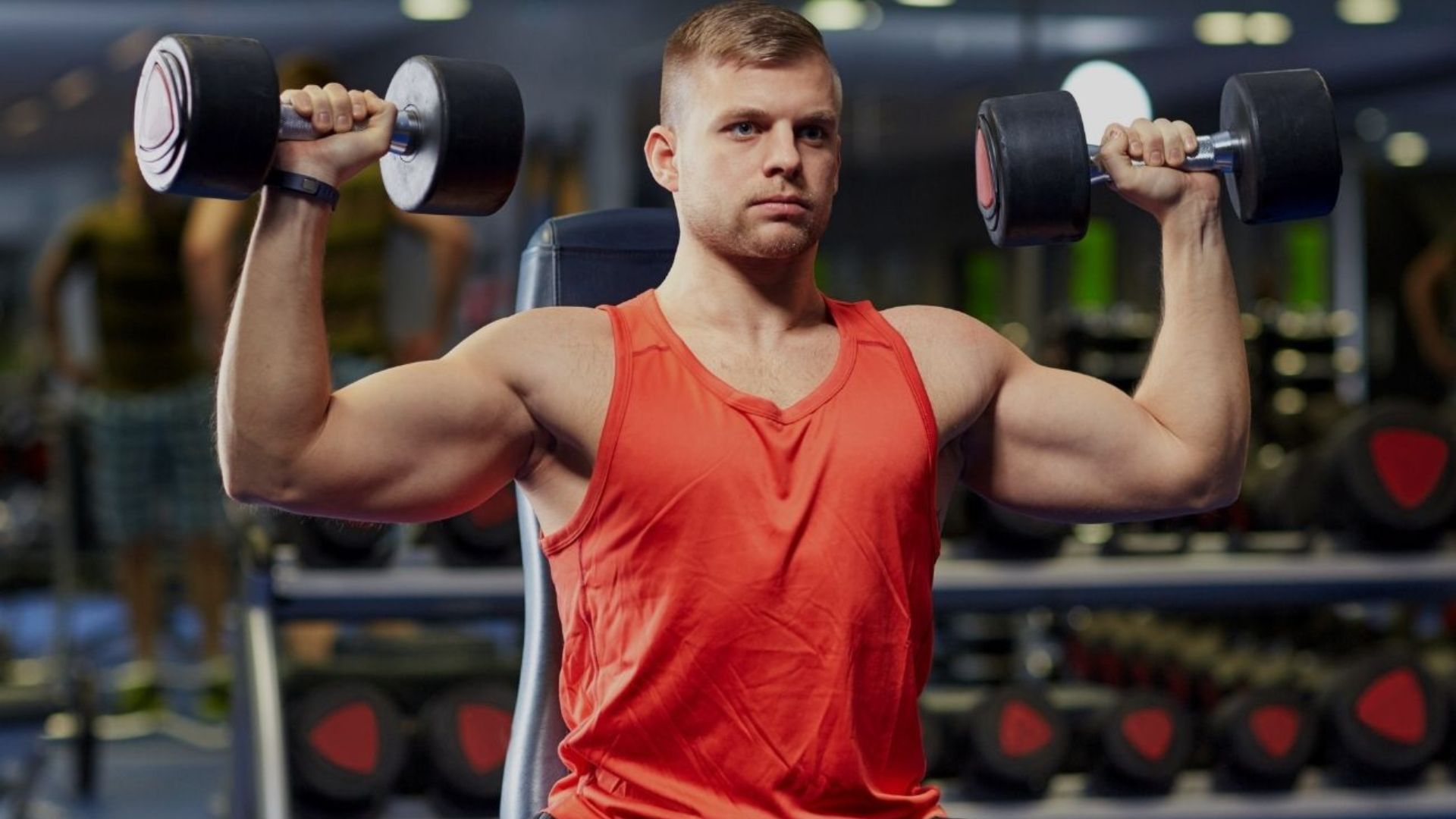 A man is lifting weights in a gym, focusing on his strength training routine.
