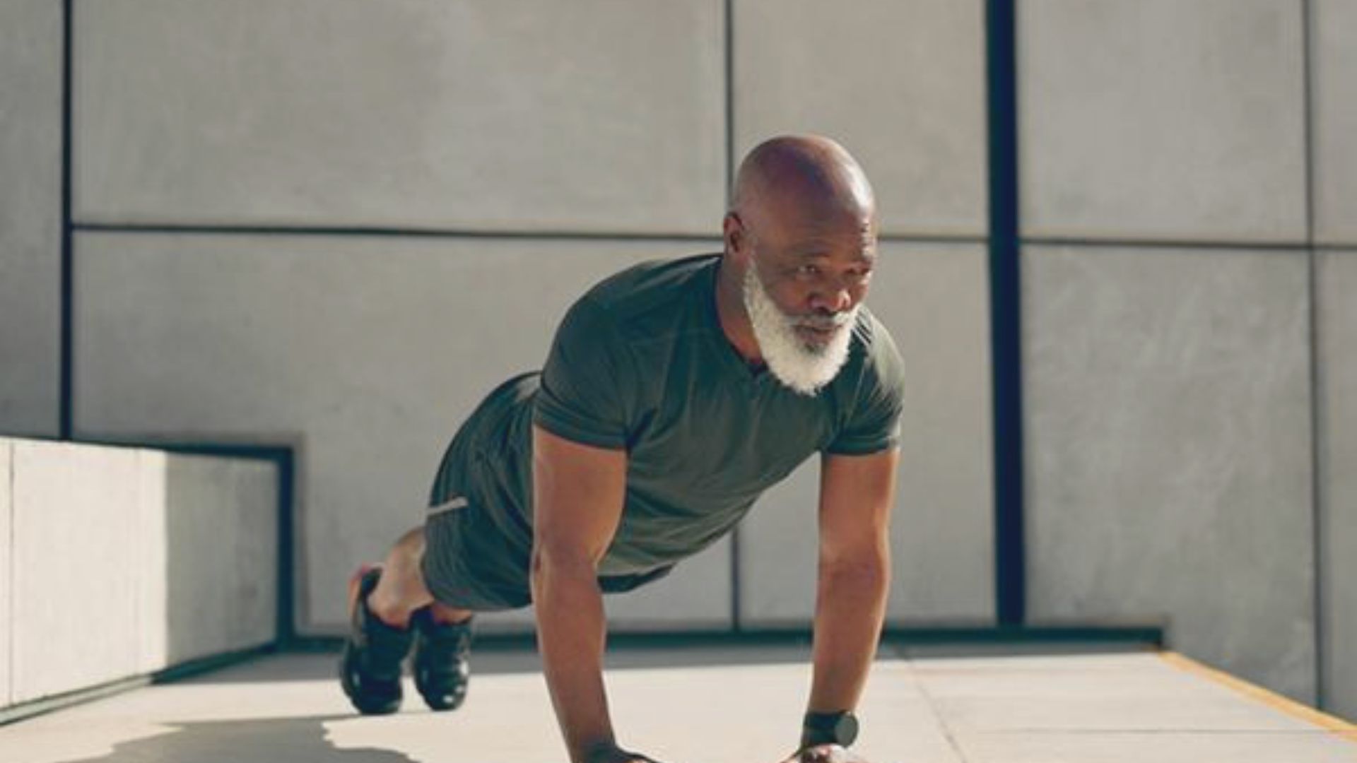 An older man performing push-ups on a concrete floor, demonstrating strength and fitness.