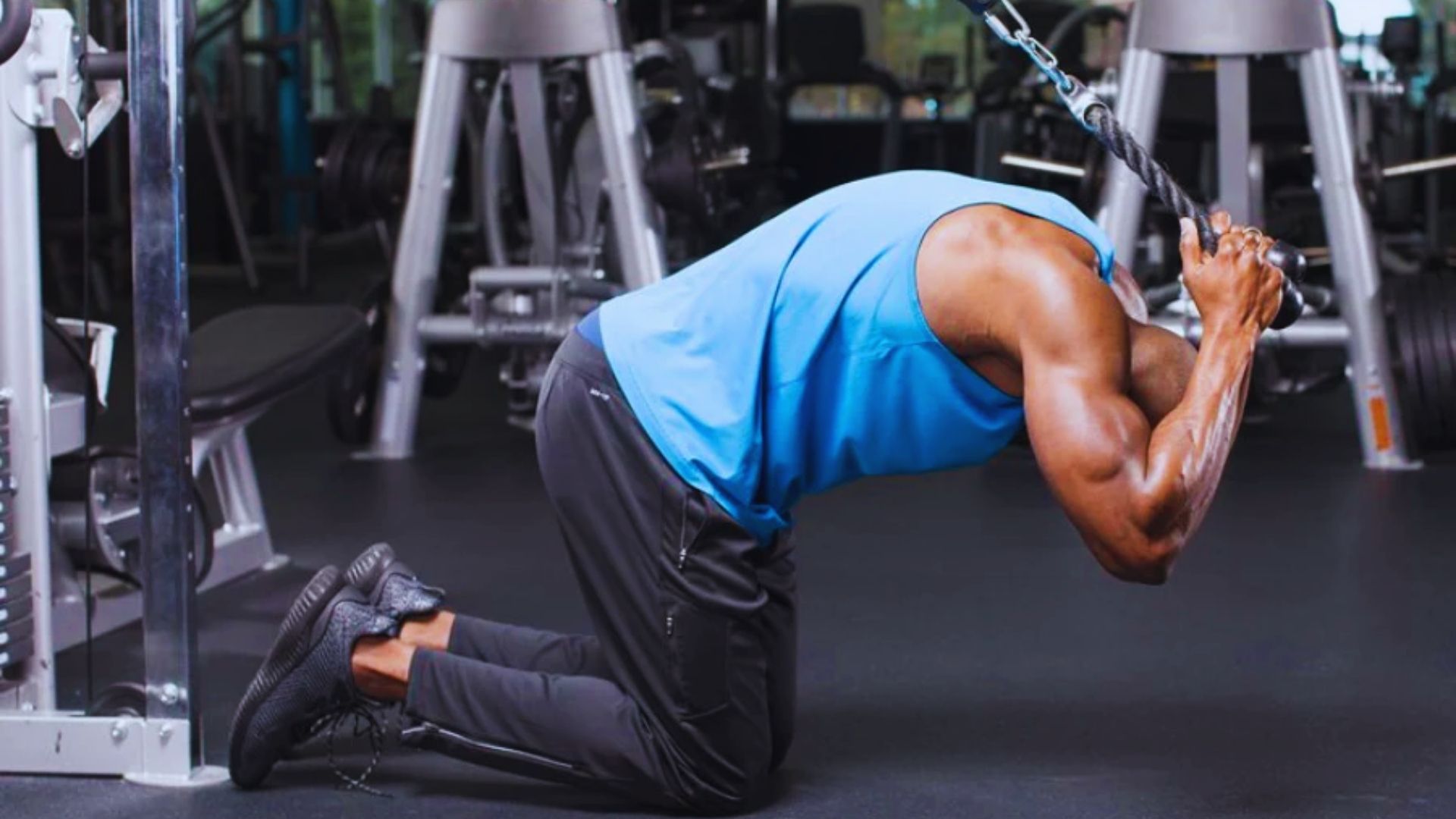 A man bends over in a gym, lifting a barbell with focused determination.