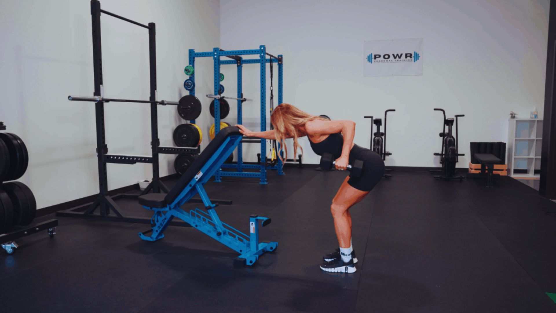 A woman performs a squat in a gym, focusing on her form and strength training.