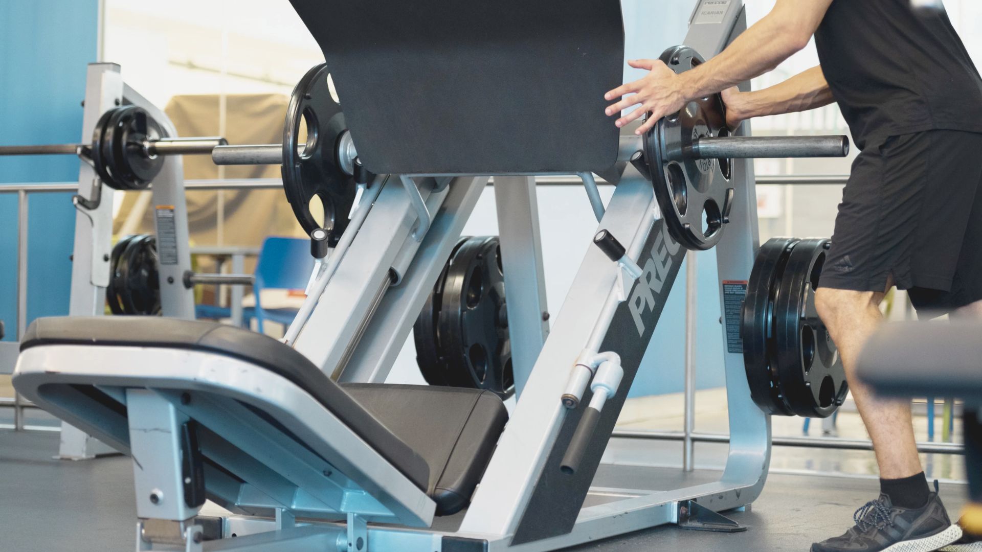 A man exercises on a bench press machine in a gym, focusing on strength training.