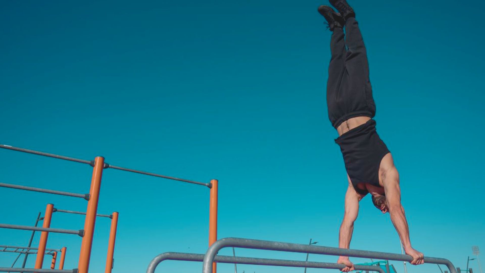 A man performing a handstand on a handrail, showcasing impressive balance and strength in an urban setting.