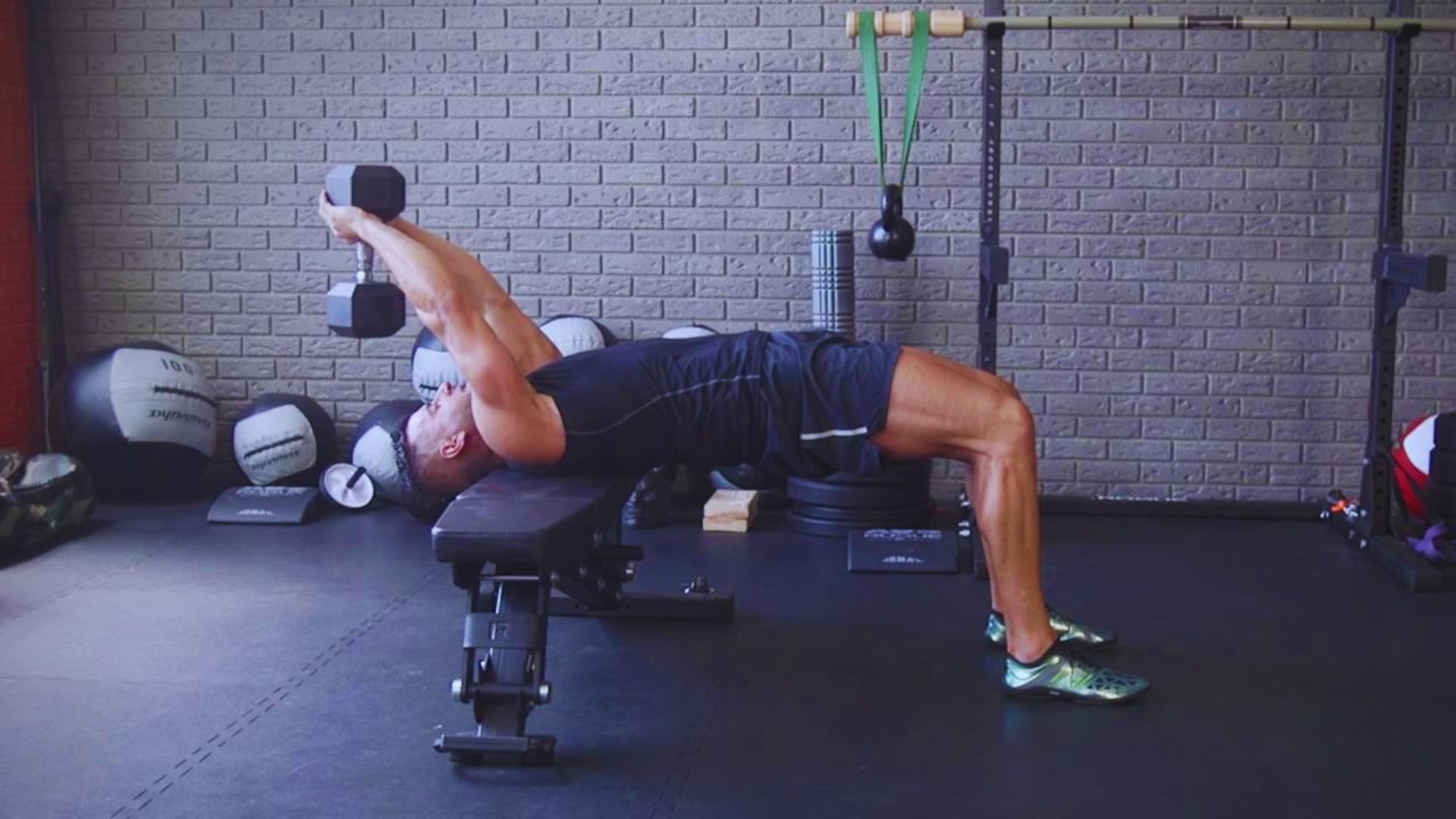 A man performing a push-up while holding dumbbells, showcasing strength and fitness in a workout setting.