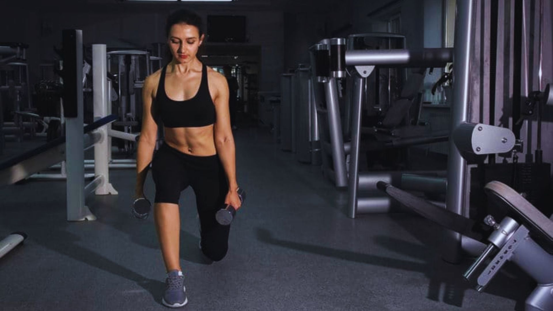A woman performs squats in a gym, focusing on her form and strength training.