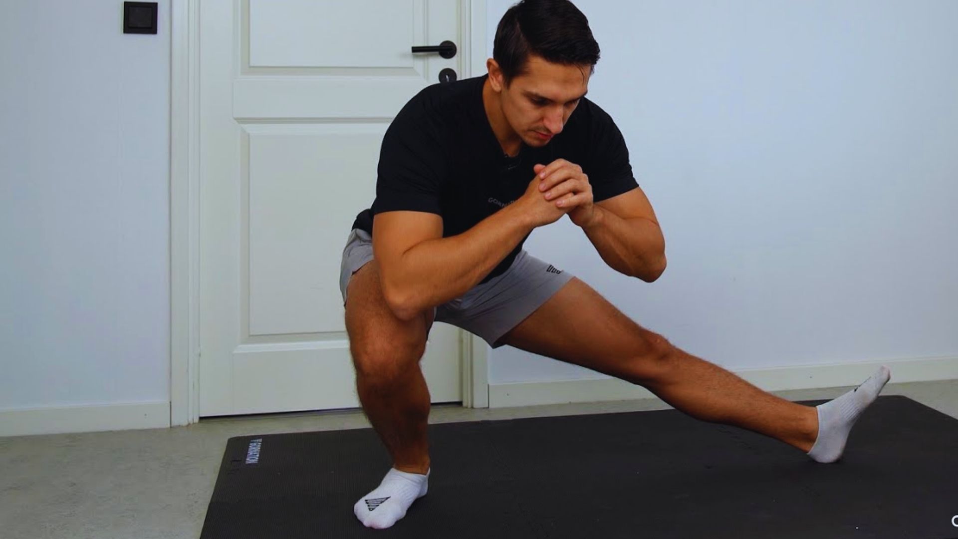 A man stretches on a mat, focusing on flexibility and balance in a fitness routine.
