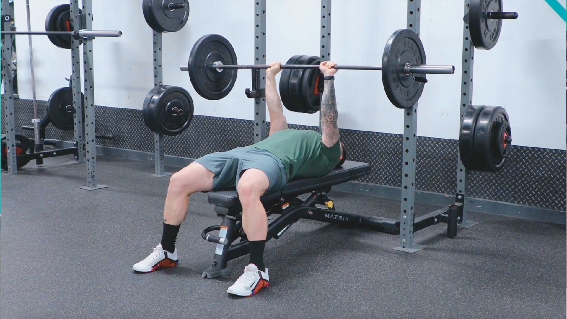 A man performs a bench press exercise in a gym, focusing on his strength training routine.