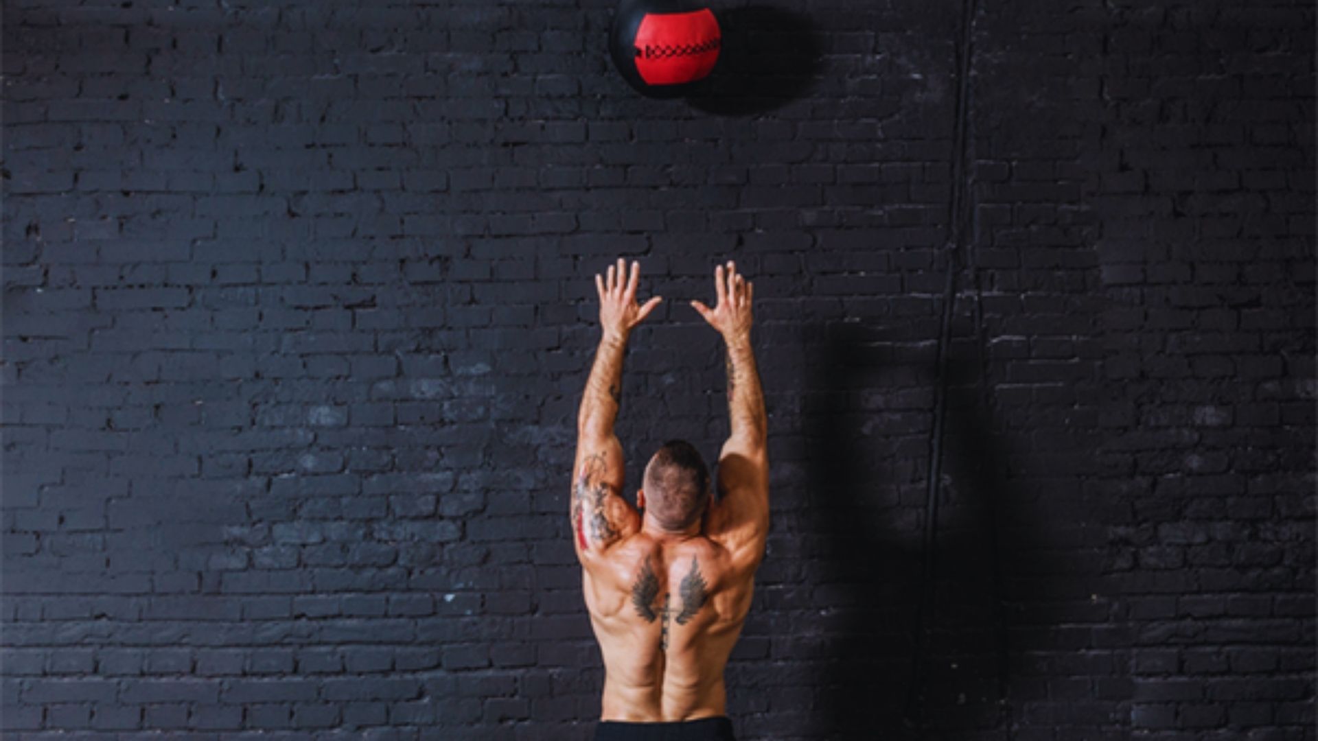 A man performs a push-up against a wall, demonstrating strength and fitness in an outdoor setting.