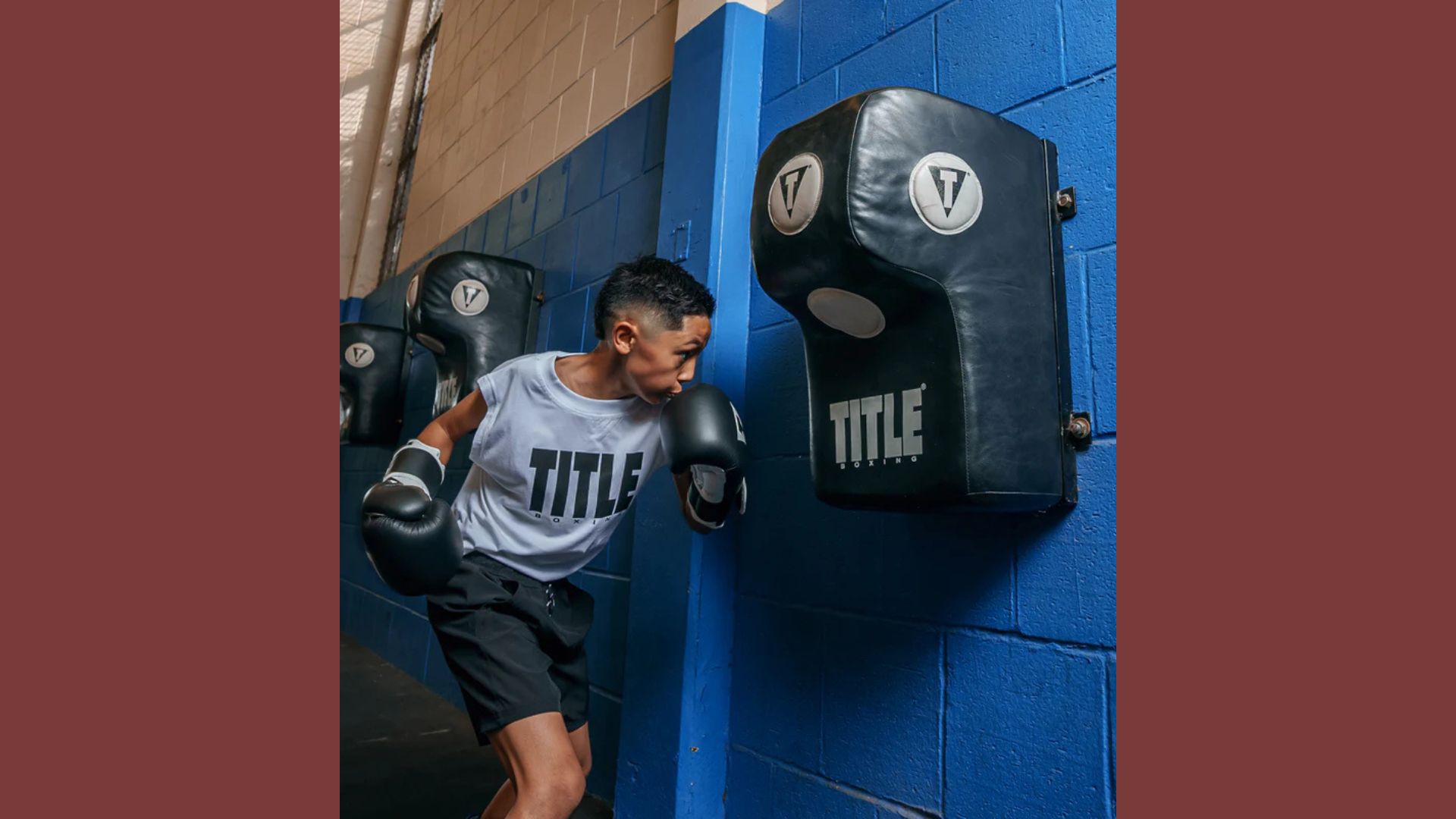 A man strikes a punching bag in a gym, showcasing his strength and focus during a workout session.