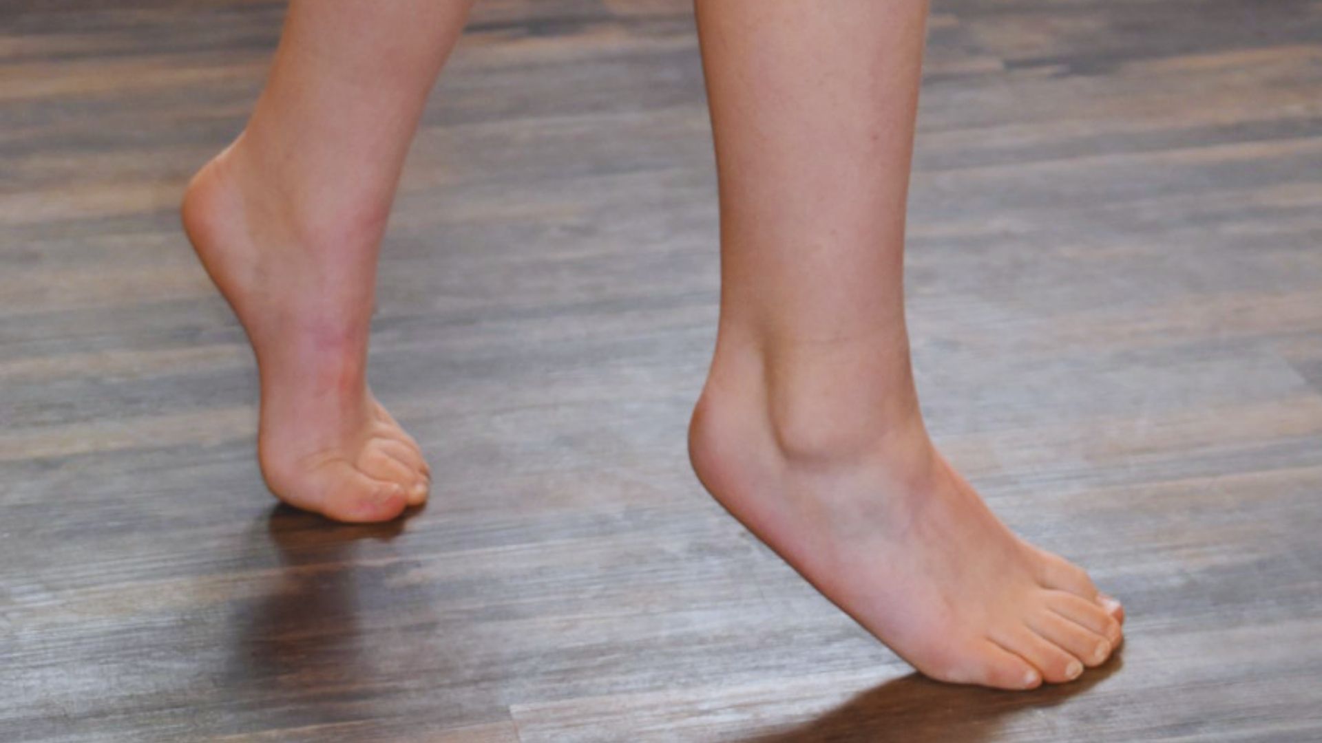 A woman's bare feet resting on a polished wooden floor, showcasing the natural texture of the wood.