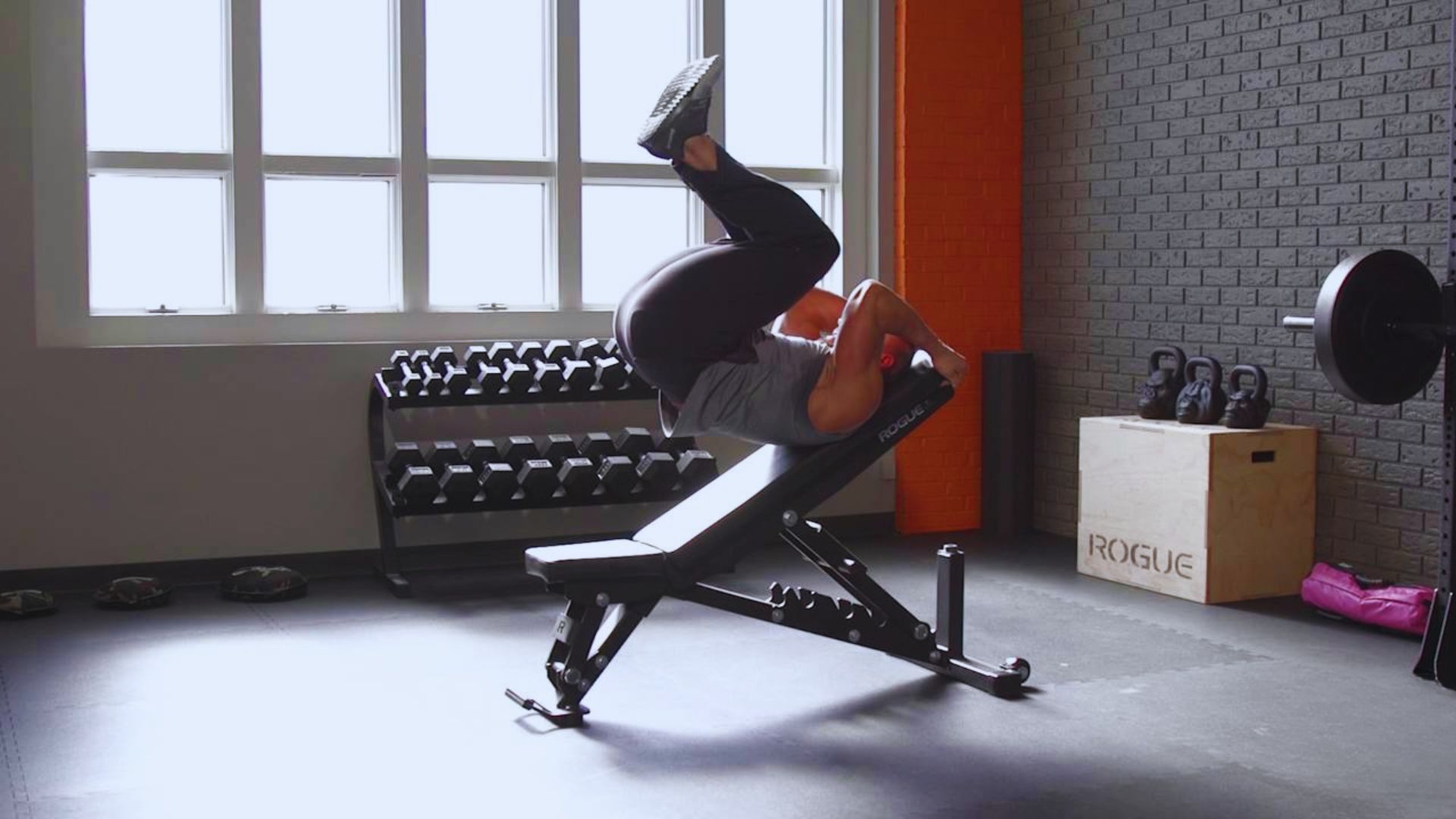 A person performing a handstand on a gym bench, showcasing strength and balance in a fitness environment.