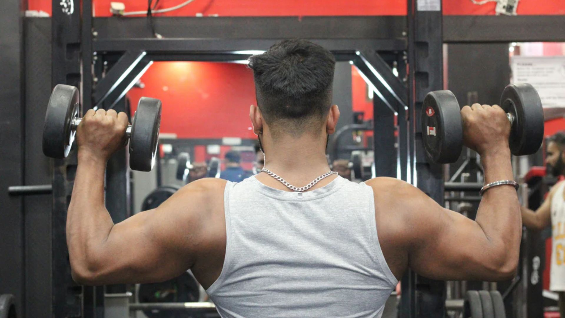 A man performs a back exercise on a gym machine, focusing on strength training and proper form.